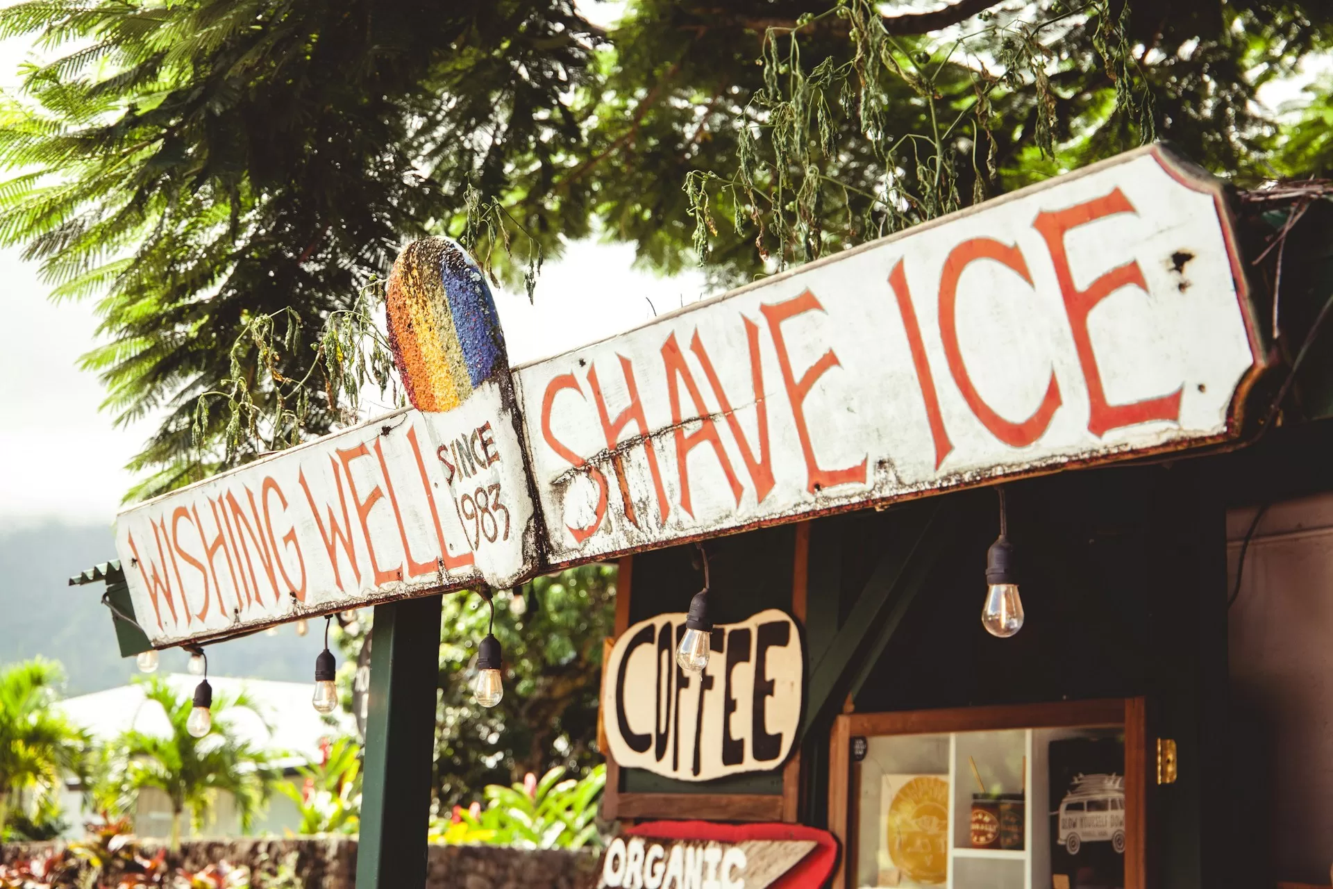 Bord van Wishing Well Shave Ice in Hawaï met kleurrijk logo en verlichting, een populaire plek voor ijs en koffie.
