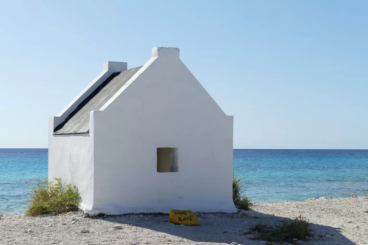 Wit slavenhuisje in Witte Pan Bonaire met de oceaan op de achtergrond.