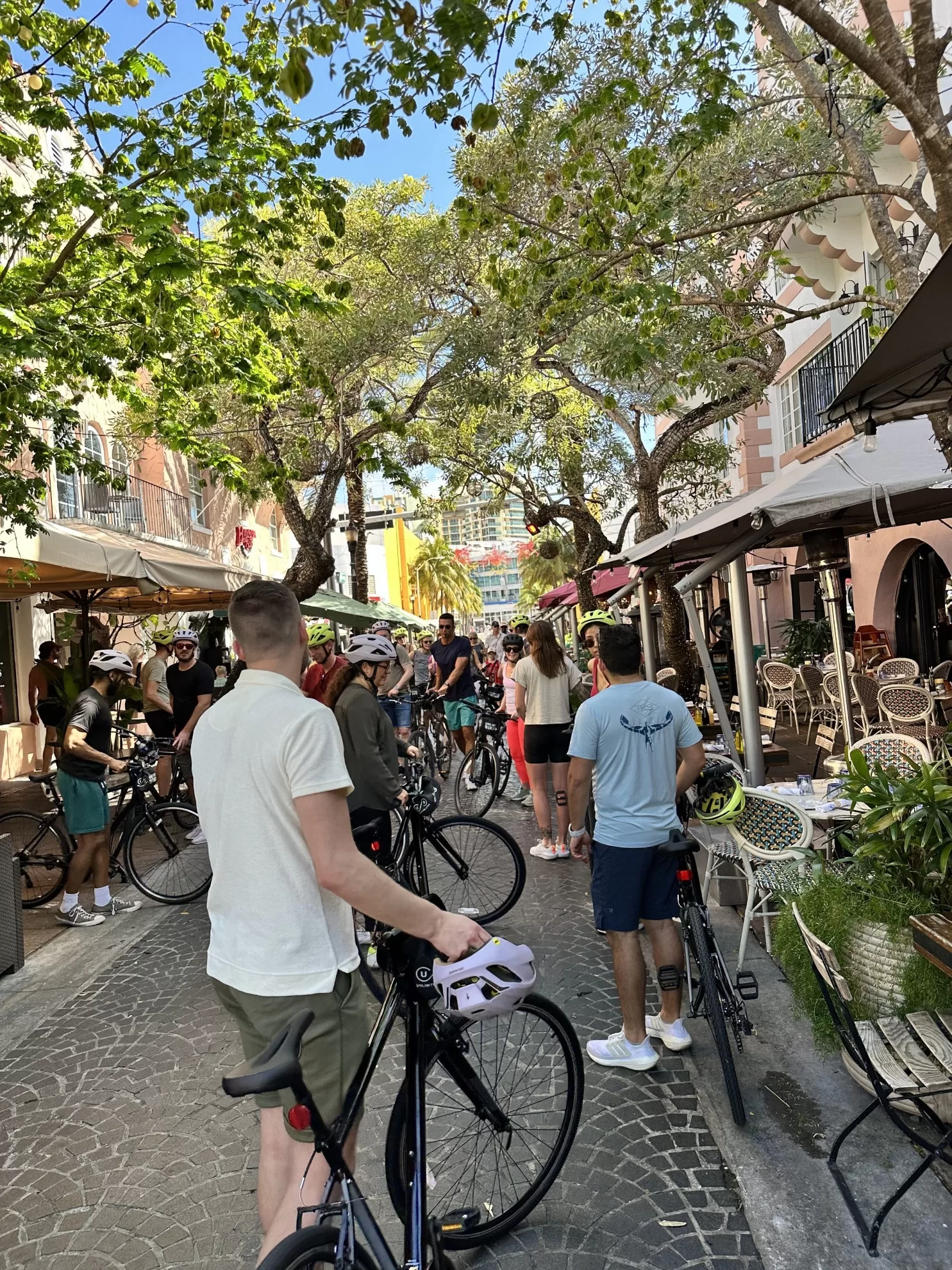 Mensen wandelen met fietsen door een zonnige straat in Miami tijdens een fietstocht