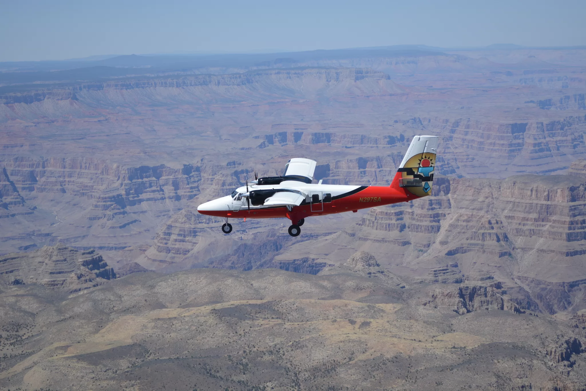 Rood-wit vliegtuig vliegt boven de Grand Canyon, luchtfoto met uitzicht op rotsformaties en diepe kloven