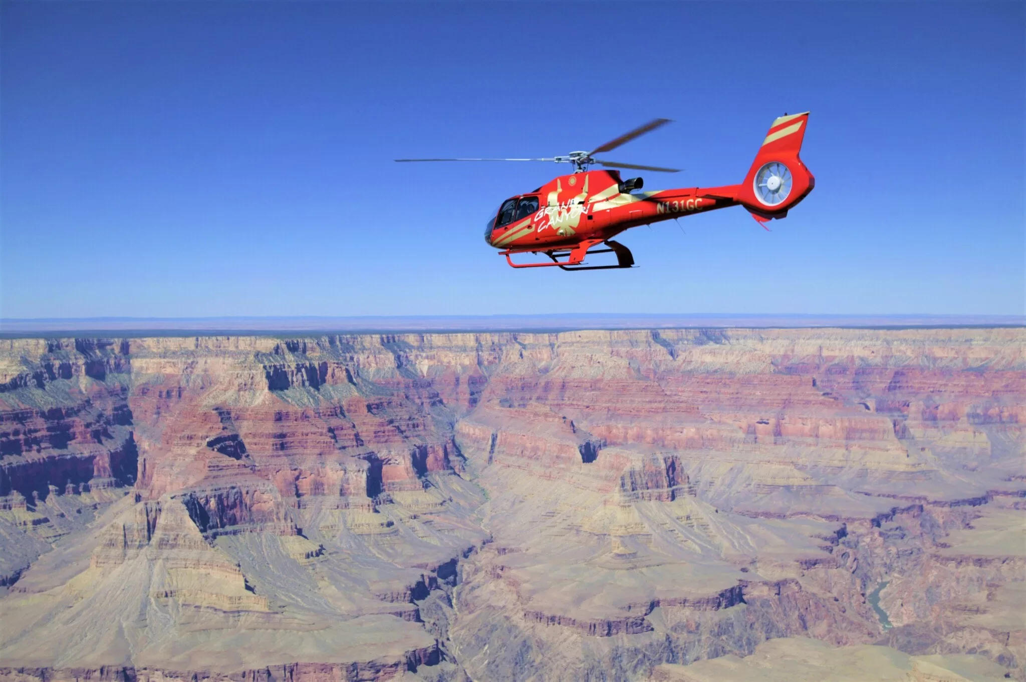 Rode helikopter vliegt boven de Grand Canyon National Park met uitzicht op de rotsformaties en kloven