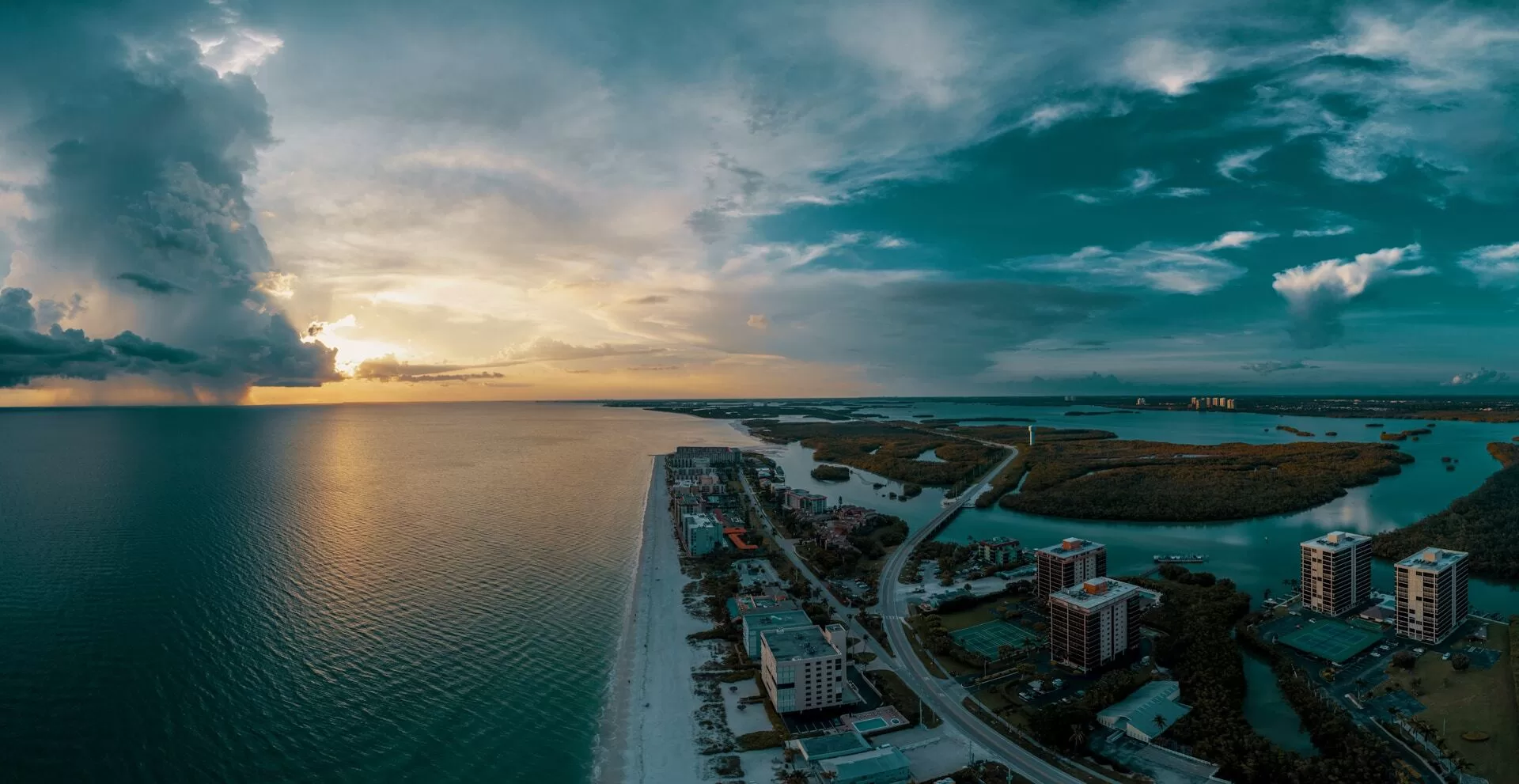 Luchtfoto van het strand van Bonita Springs met ondergaande zon op de achtergrond.