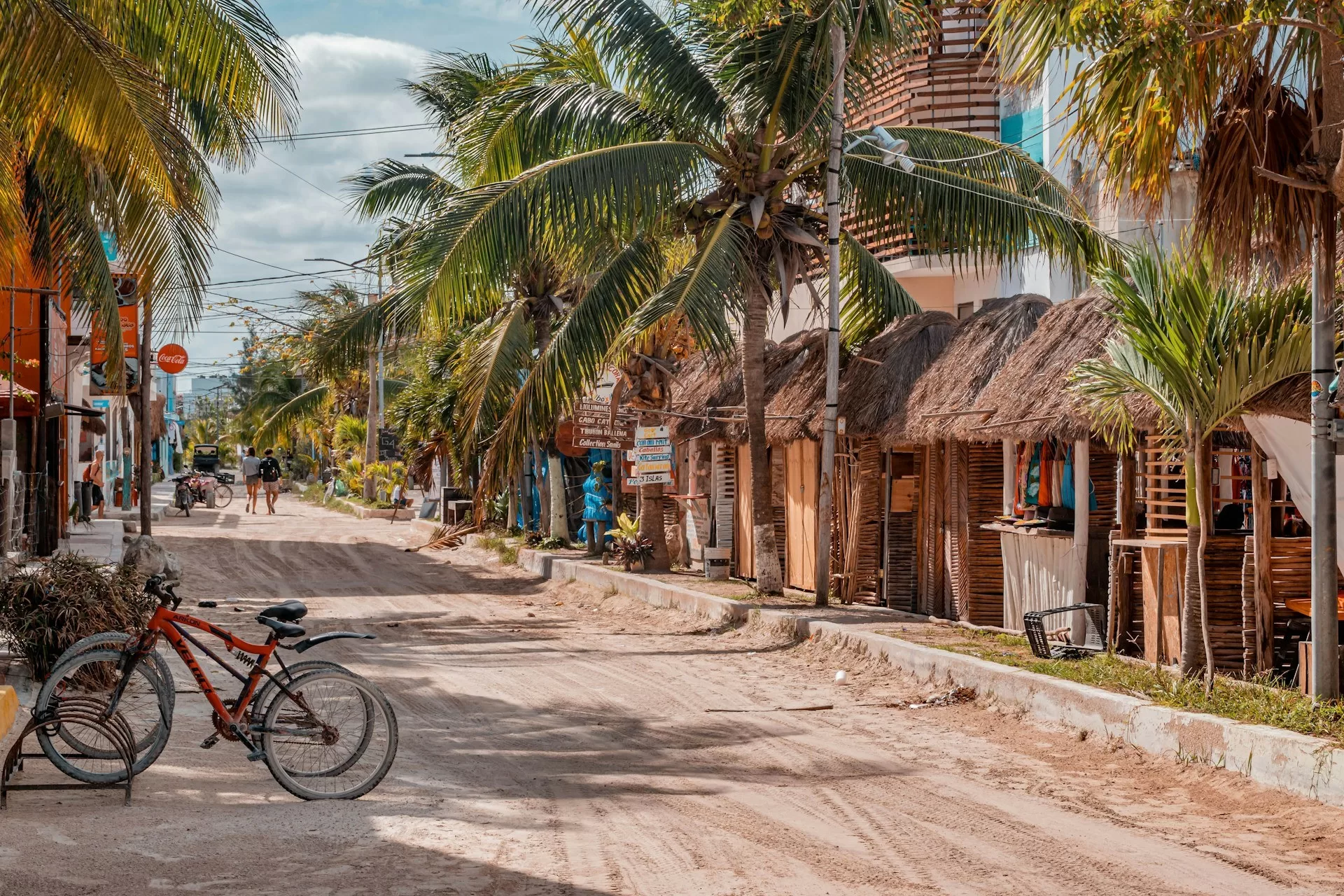 Zandweg met huisjes, palmen en fietsen op Holbox, Mexico