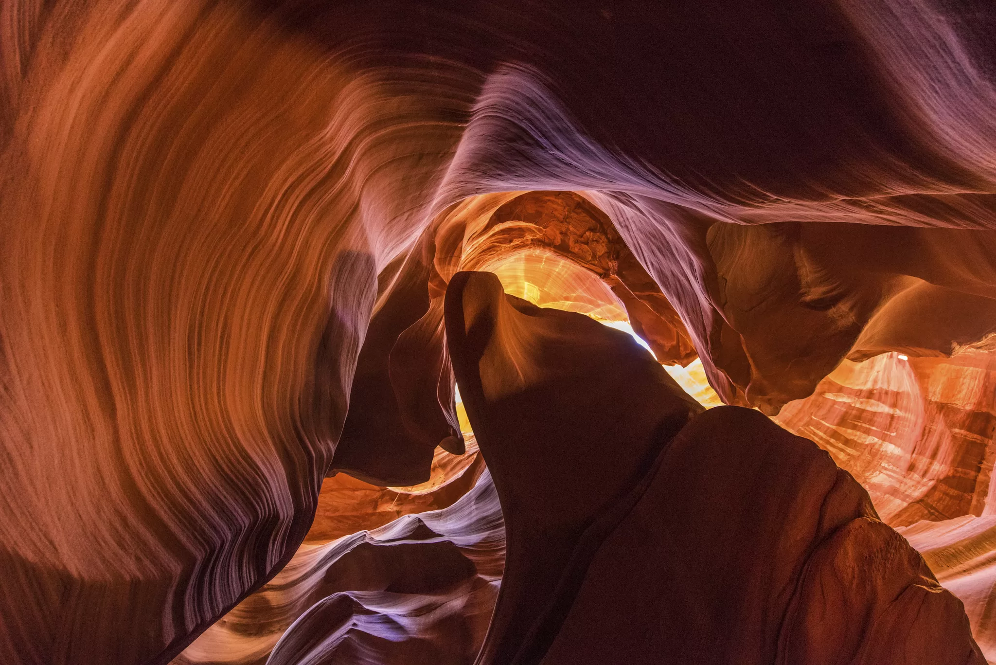 Uitzicht van beneden naar boven in Antelope Canyon met zonlicht tussen smalle, golvende rode rotswanden.