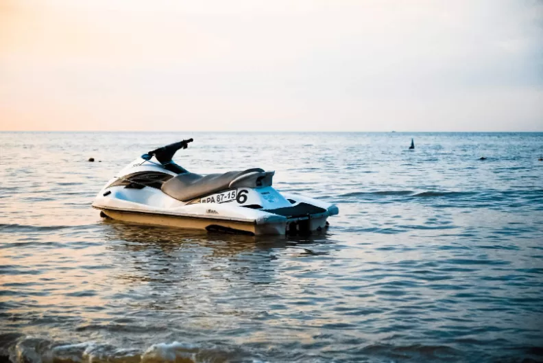Lege jetski op het water bij zachte zonsondergang, met vogels in de verte op een rustige avond