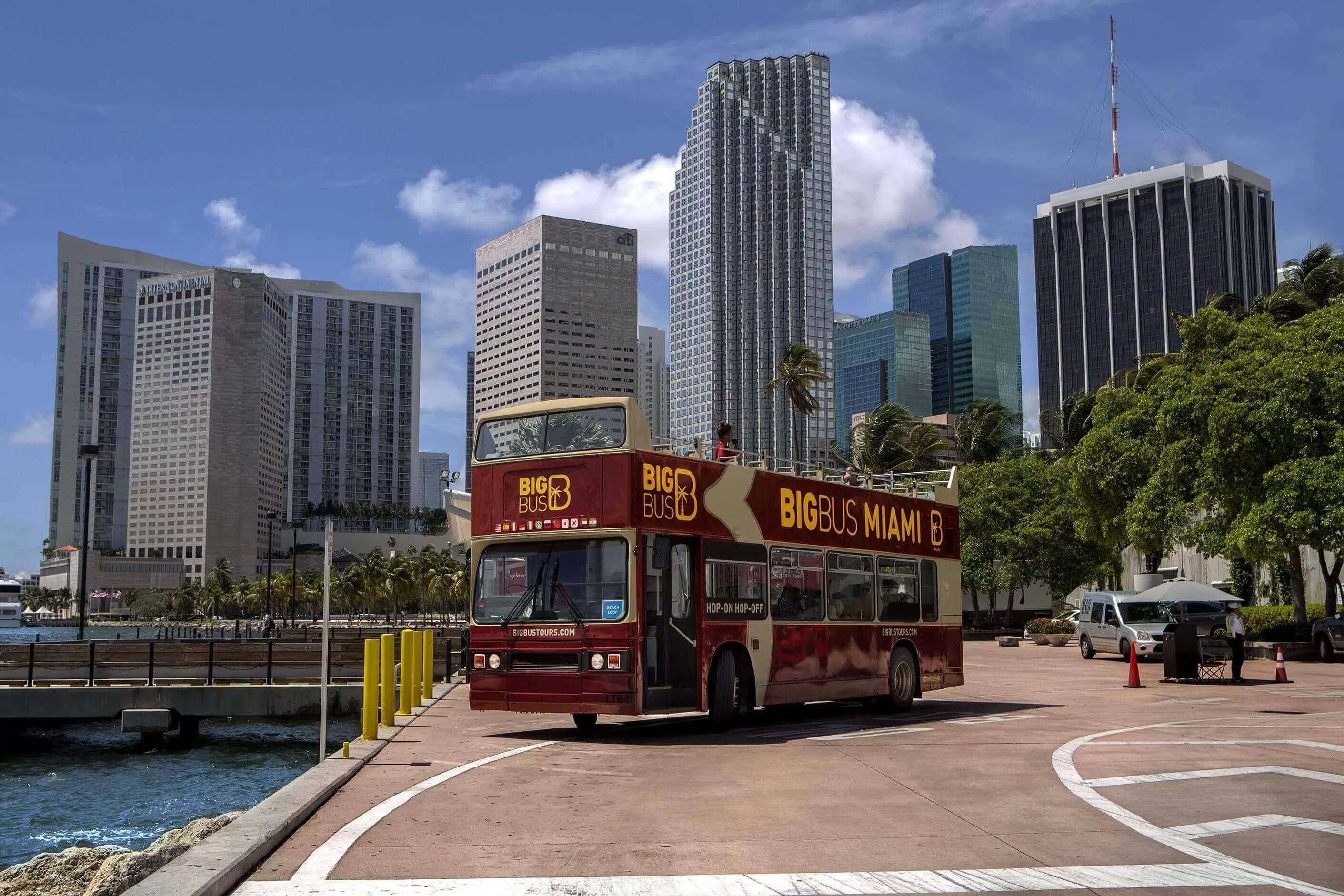 Hop-on hop-off bus in Miami met hoge wolkenkrabbers op de achtergrond tijdens zonnige dag