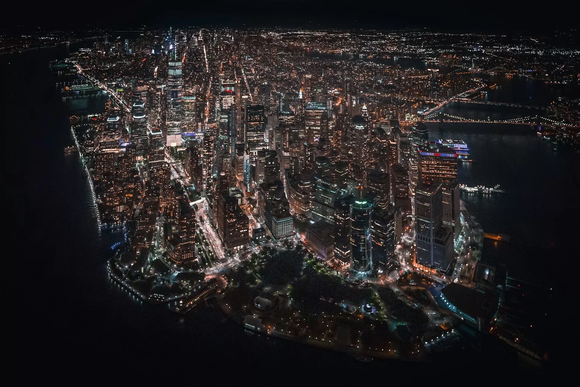 Luchtfoto van verlicht New York in het donker, stadslichten en skyline zichtbaar, nachtelijke sfeer boven de stad