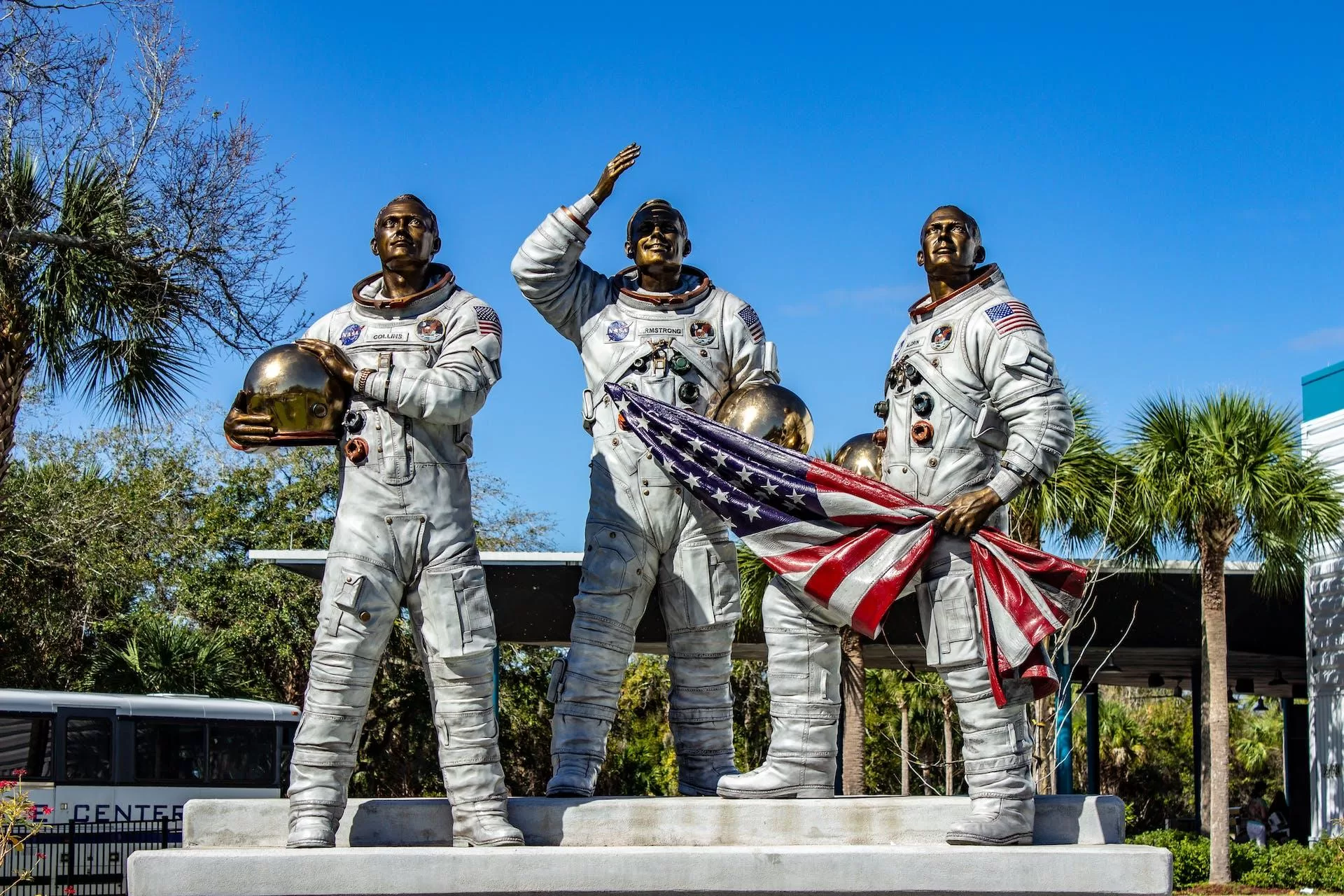Standbeeld van drie astronauten met helmen en Amerikaanse vlaggen, symbolisch voor ruimtevaart en NASA