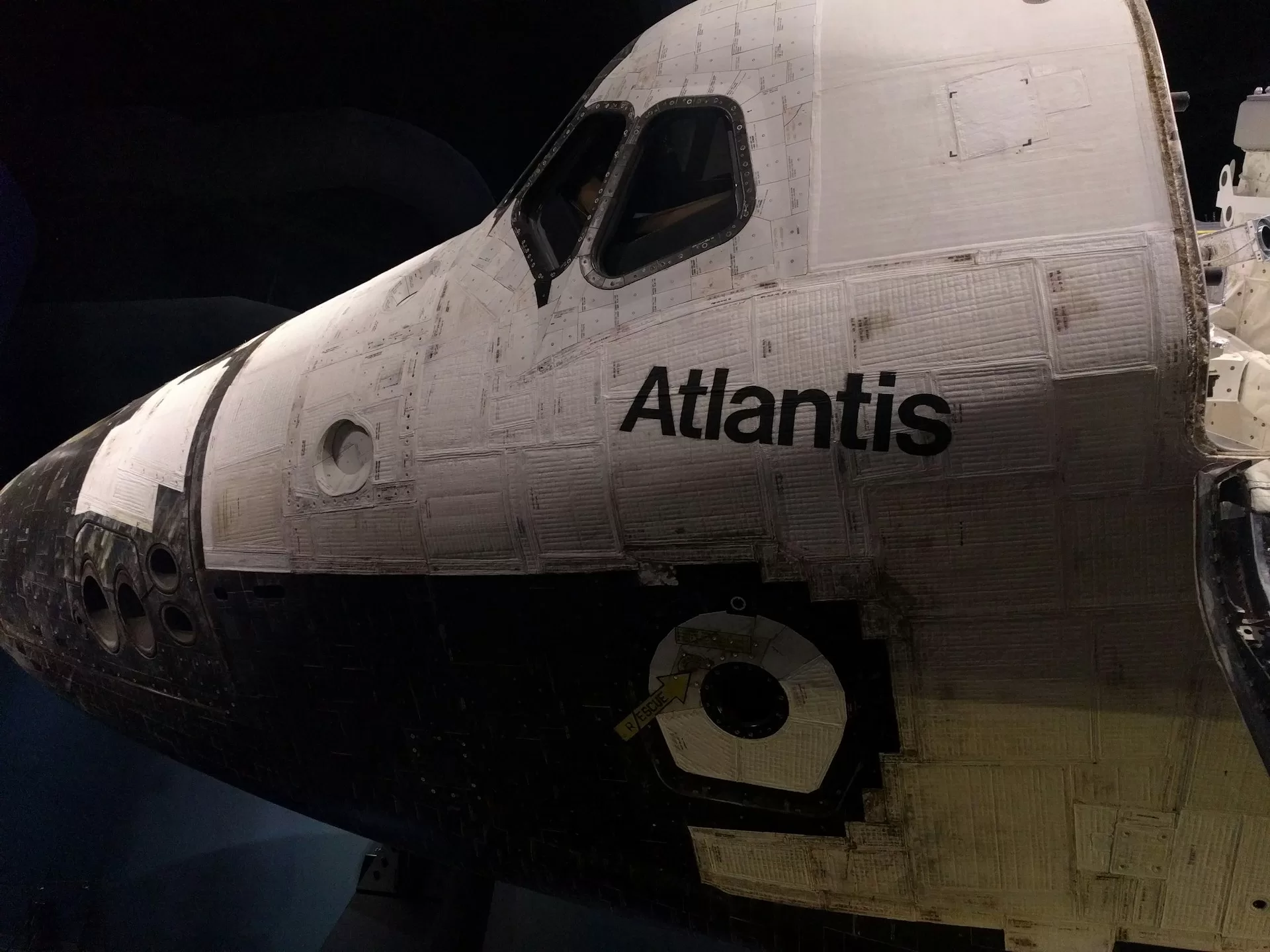 Voorzijde van spaceshuttle Atlantis met zicht op cockpit en hittebestendige tegels in ruimtevaartmuseum