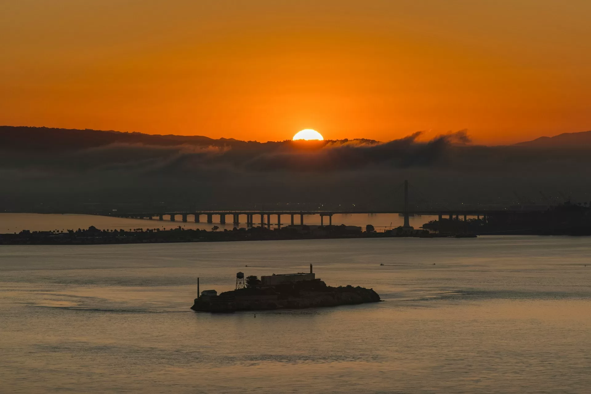 Golden Gate Bridge bij schemering met oranje lucht en ondergaande zon