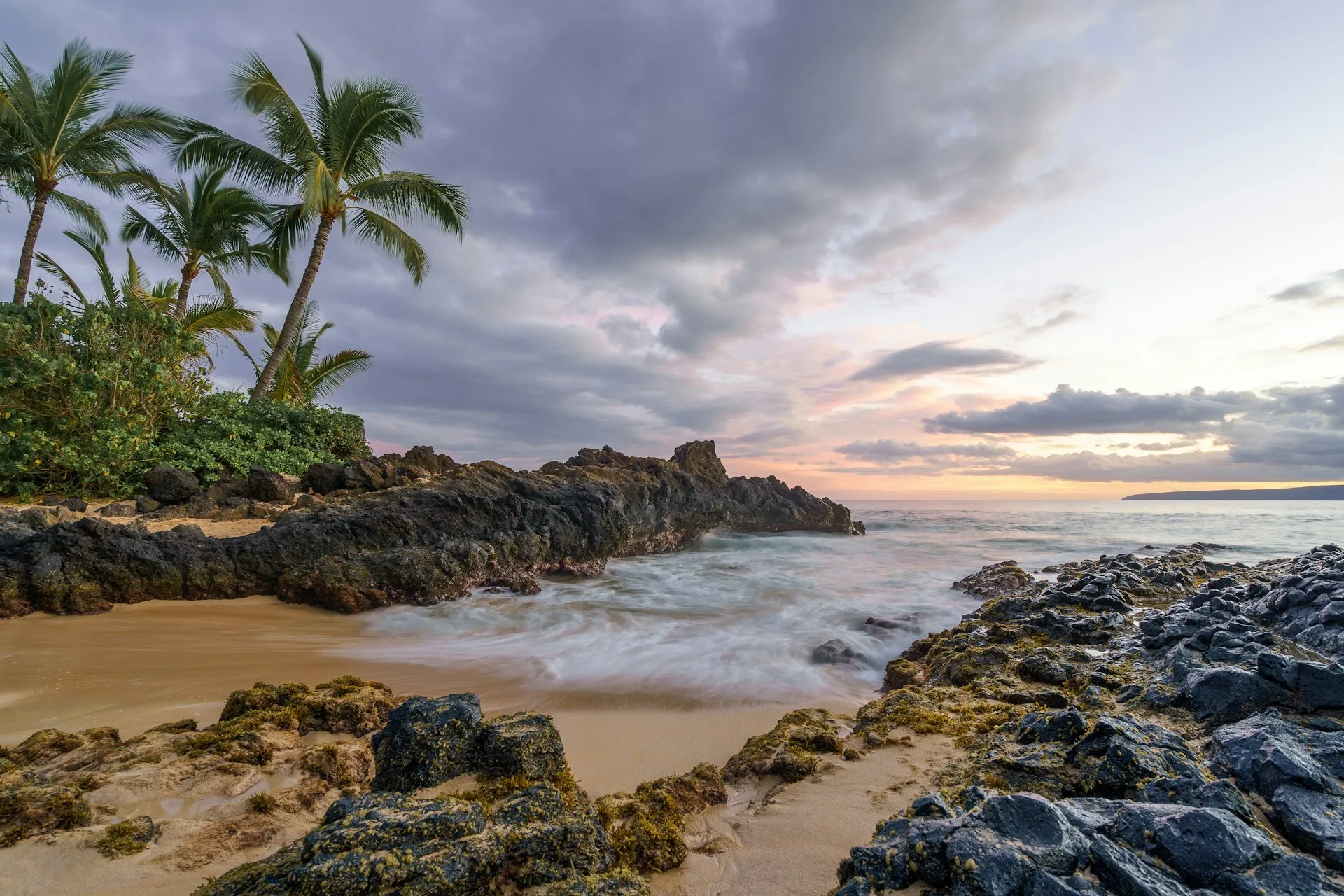 Een tropisch strand op Maui, Hawaii, met helderblauw water en ruige rotsen langs de kust