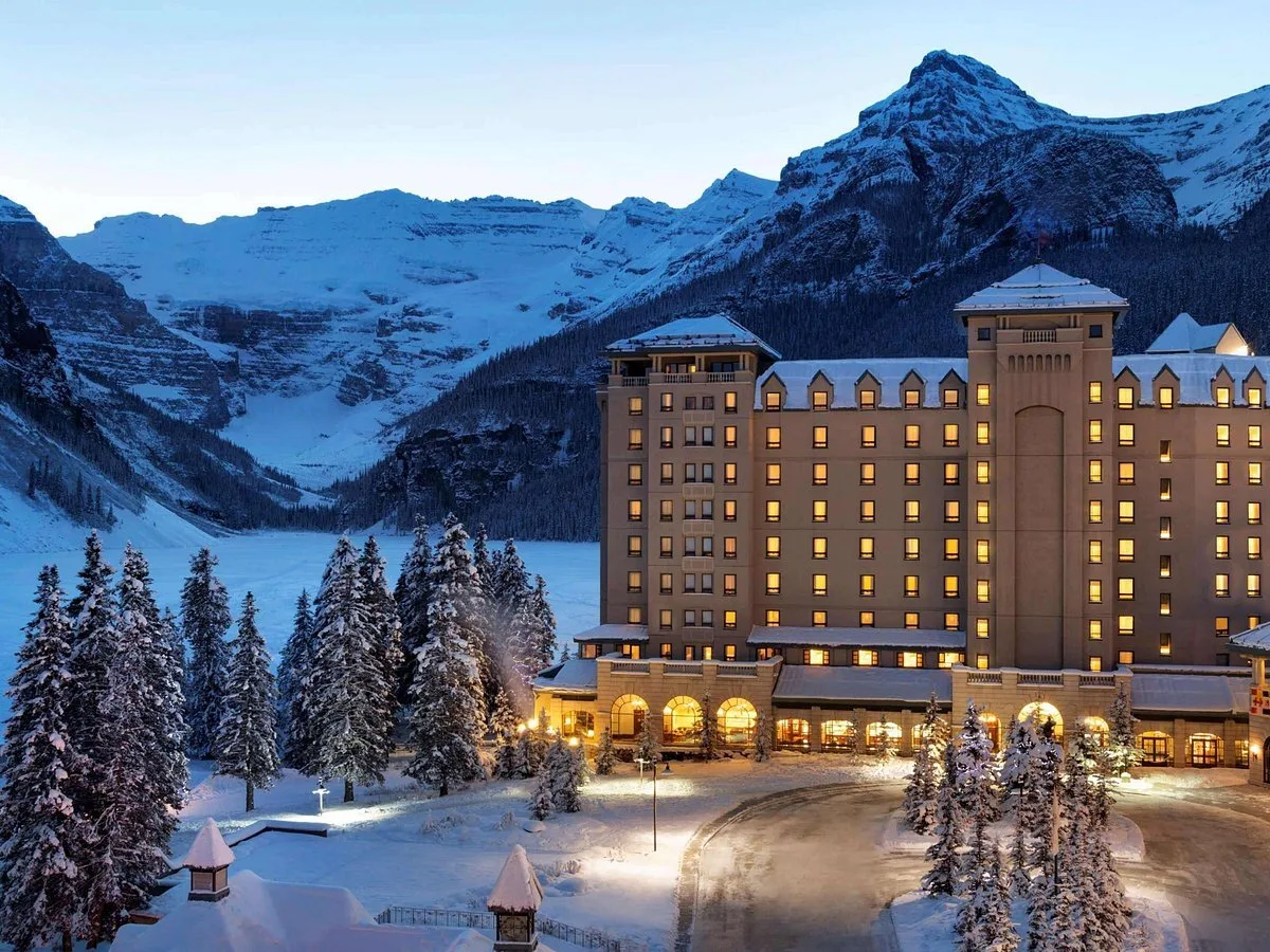 Vooraanzicht van het Hotel Fairmont Château Lake Louise met besneeuwde bergen op de achtergrond