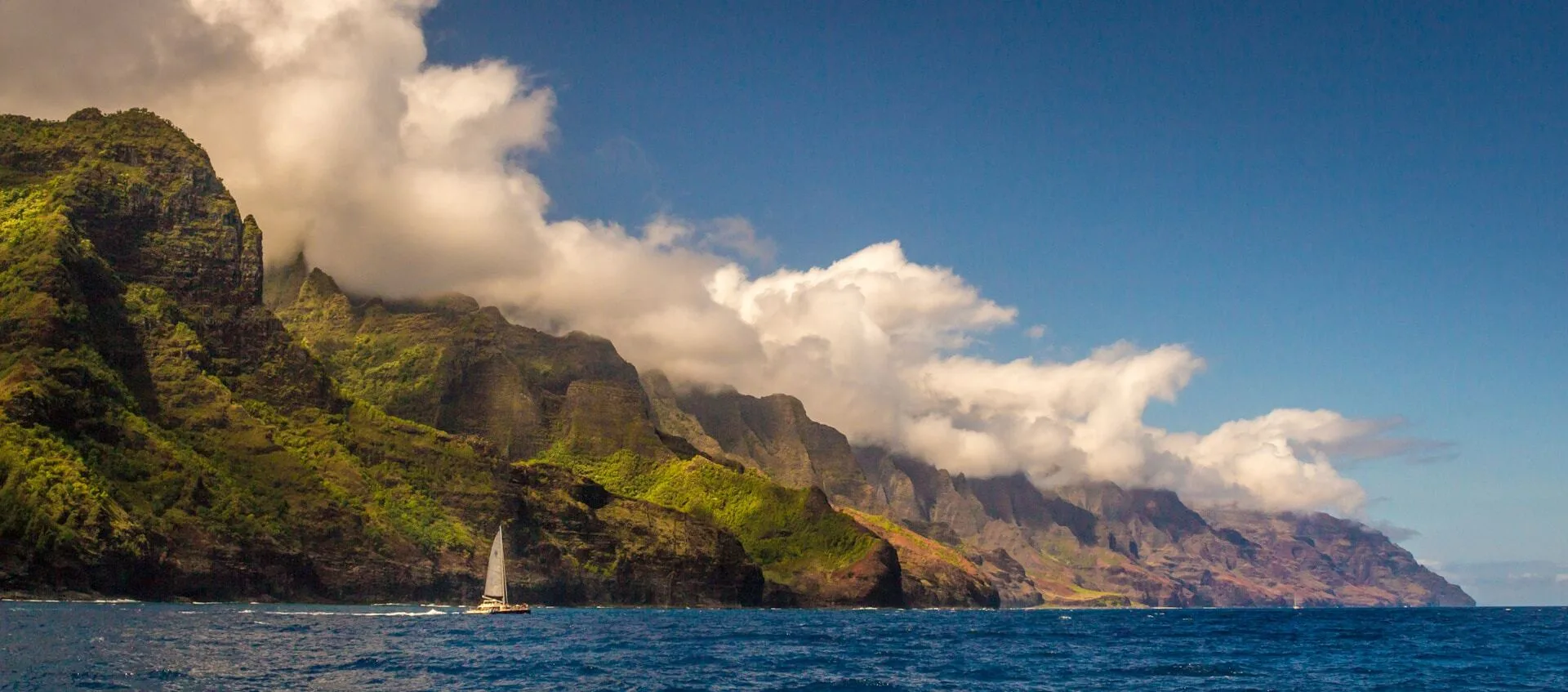 Bergen met groene planten en een zeilboot langs de kust van Kapaa, Kauai