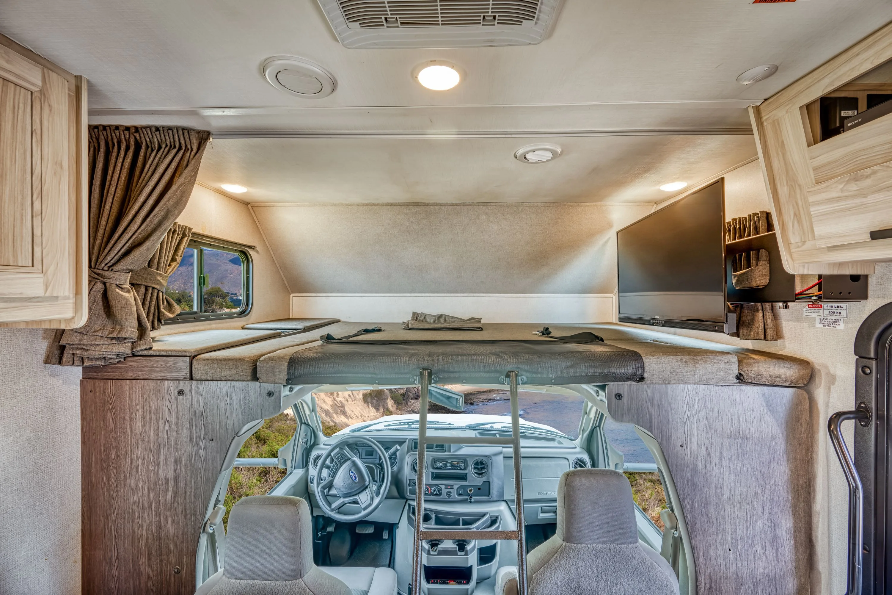 Het bed boven de rijdersstoel in een Road Bear camper