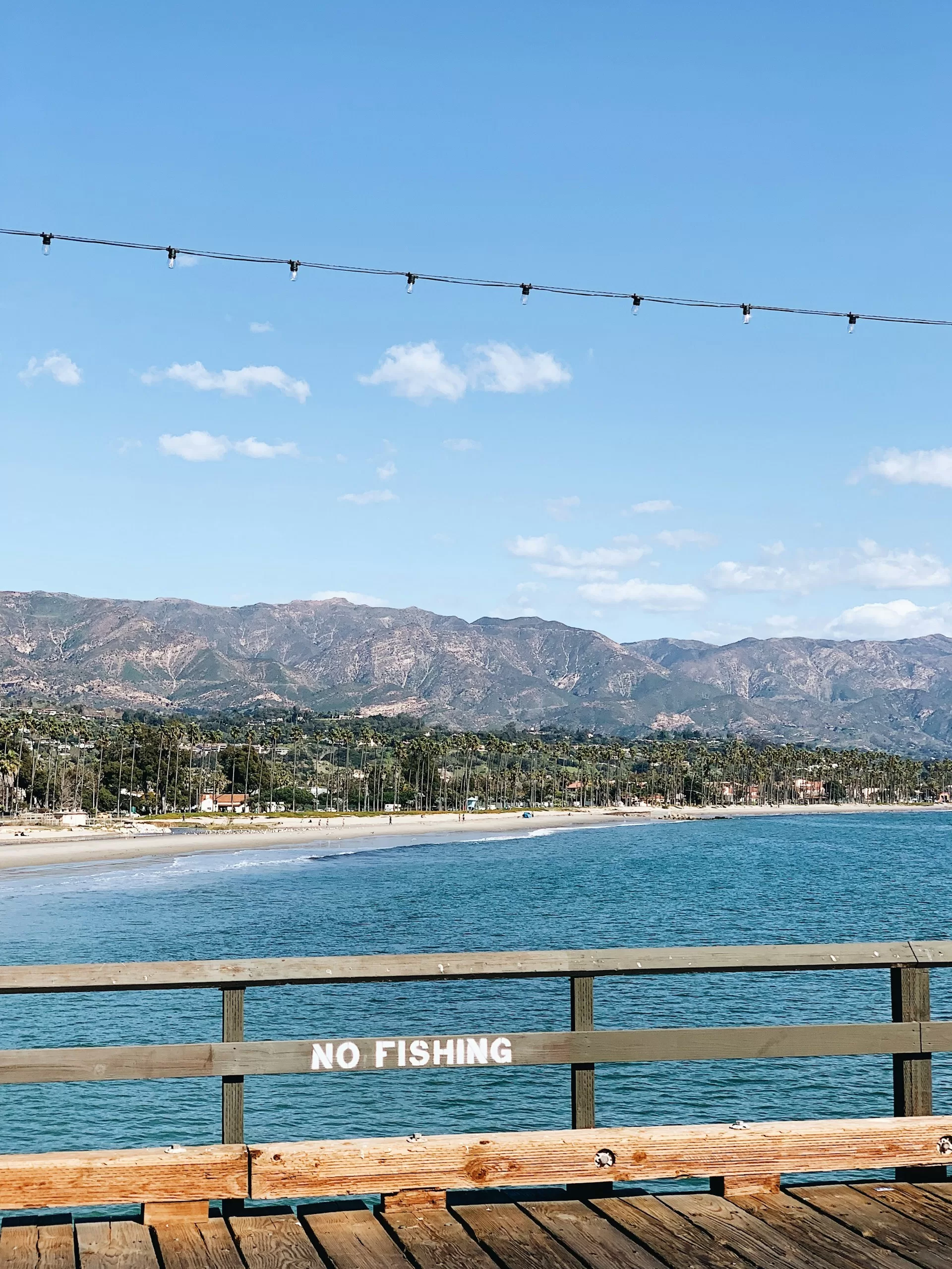 Uitzicht vanaf een steiger over het strand van Santa Barbara met bergen op de achtergrond
