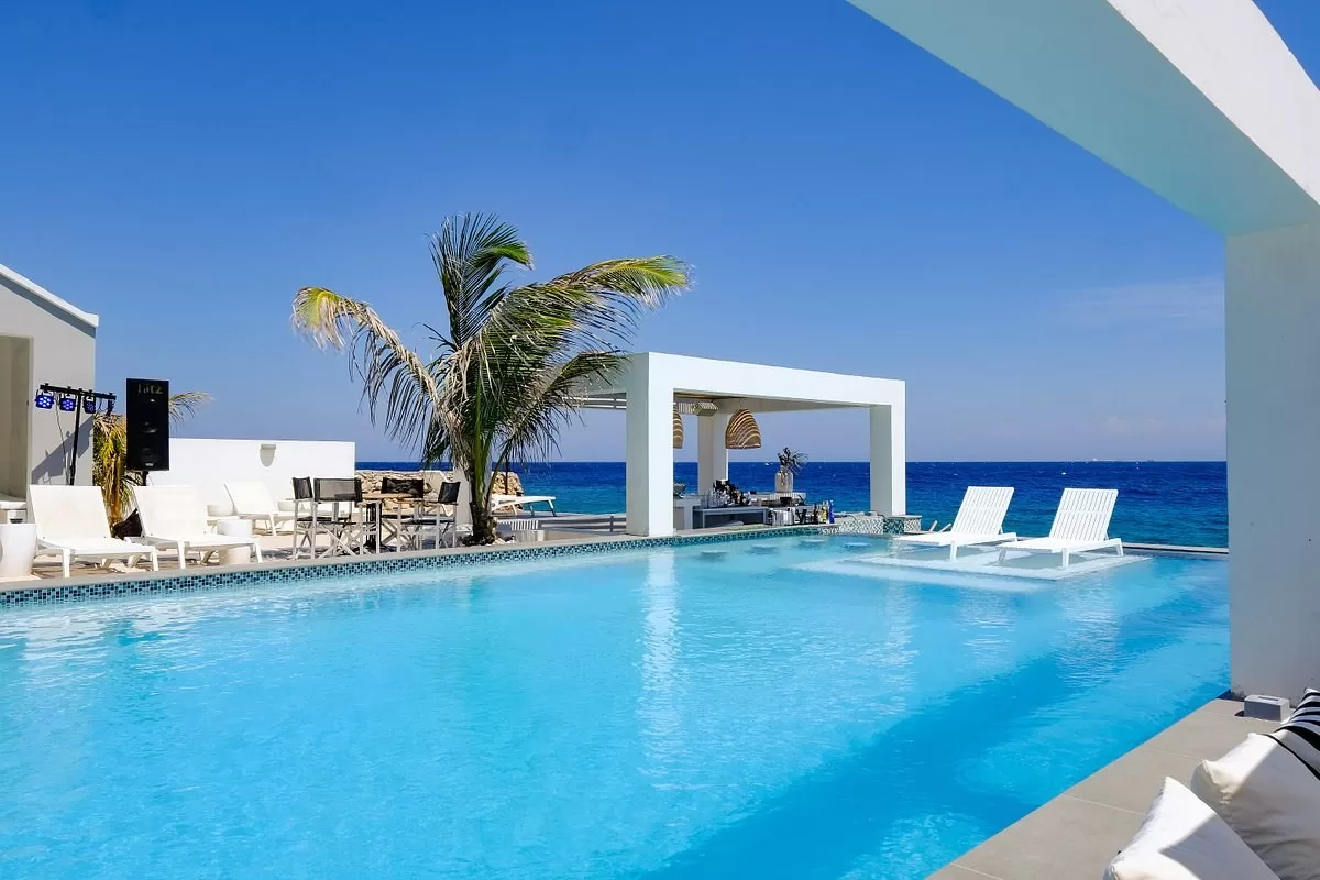 Buitenzwembad met loungestoelen en uitzicht op de oceaan in het Hotel Saint Tropez Boutique Hotel