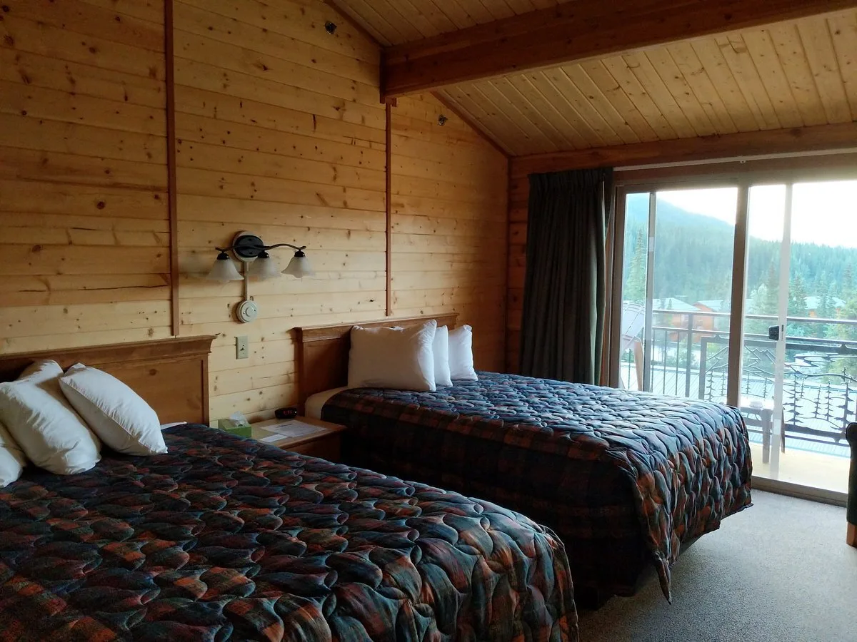 Standaardkamer met twee aparte bedden en glazen schuifdeuren naar het balkon in het Hotel Grizzly Bear Resort