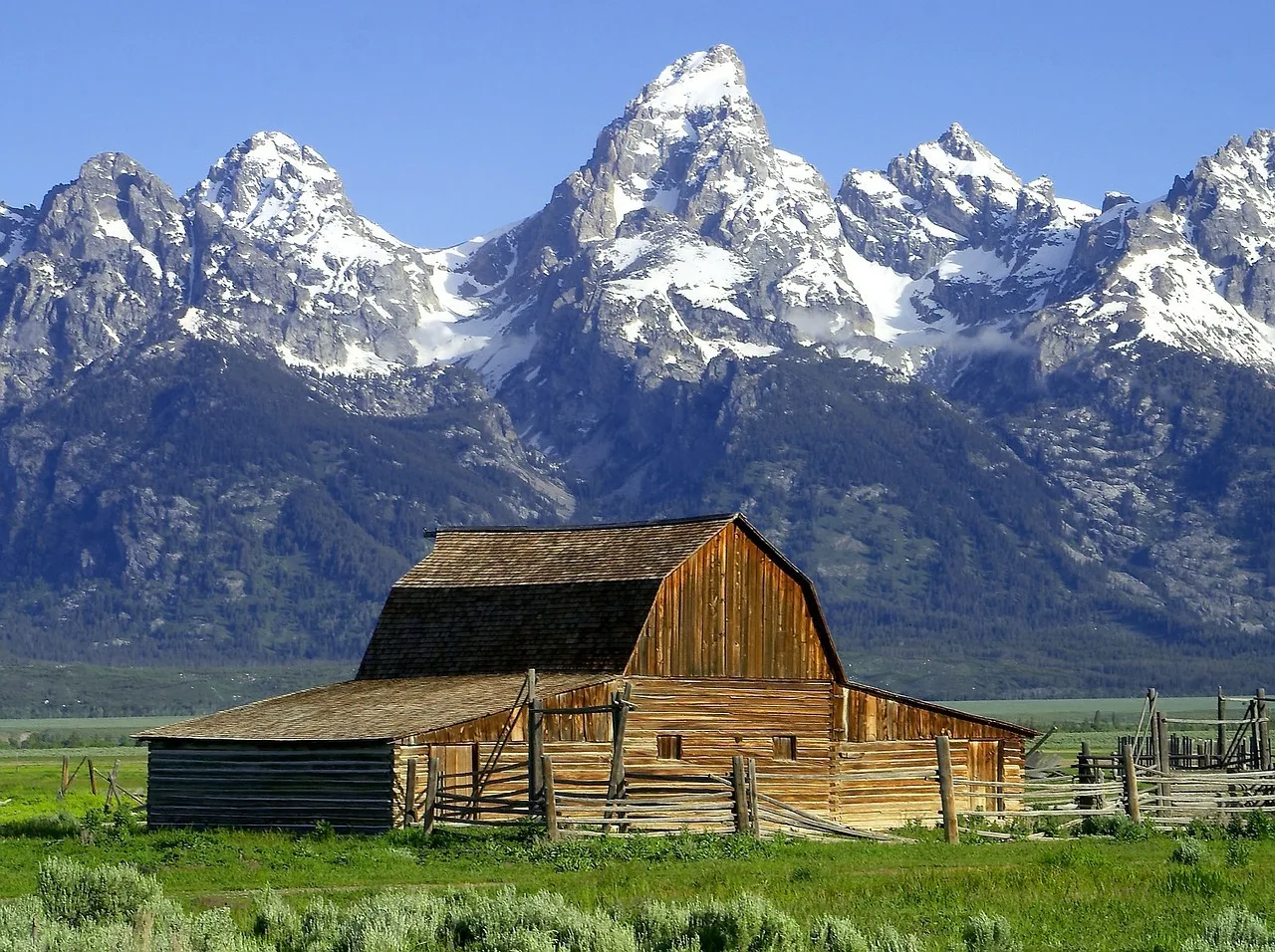 Houten schuur in Grand Teton National Park met de besneeuwde bergtoppen op de achtergrond.