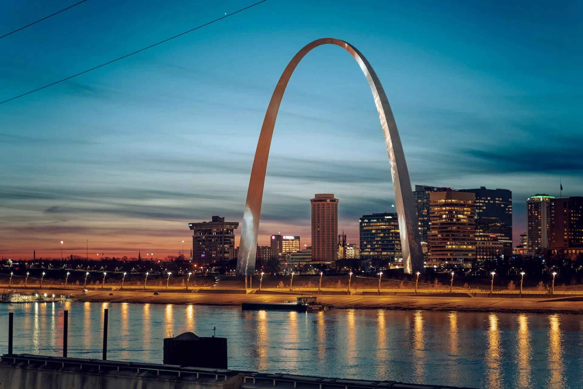 Uitzicht tijdens zonsondergang op de Gateway Arch in St. Louis met de Mississippi River op de voorgrond