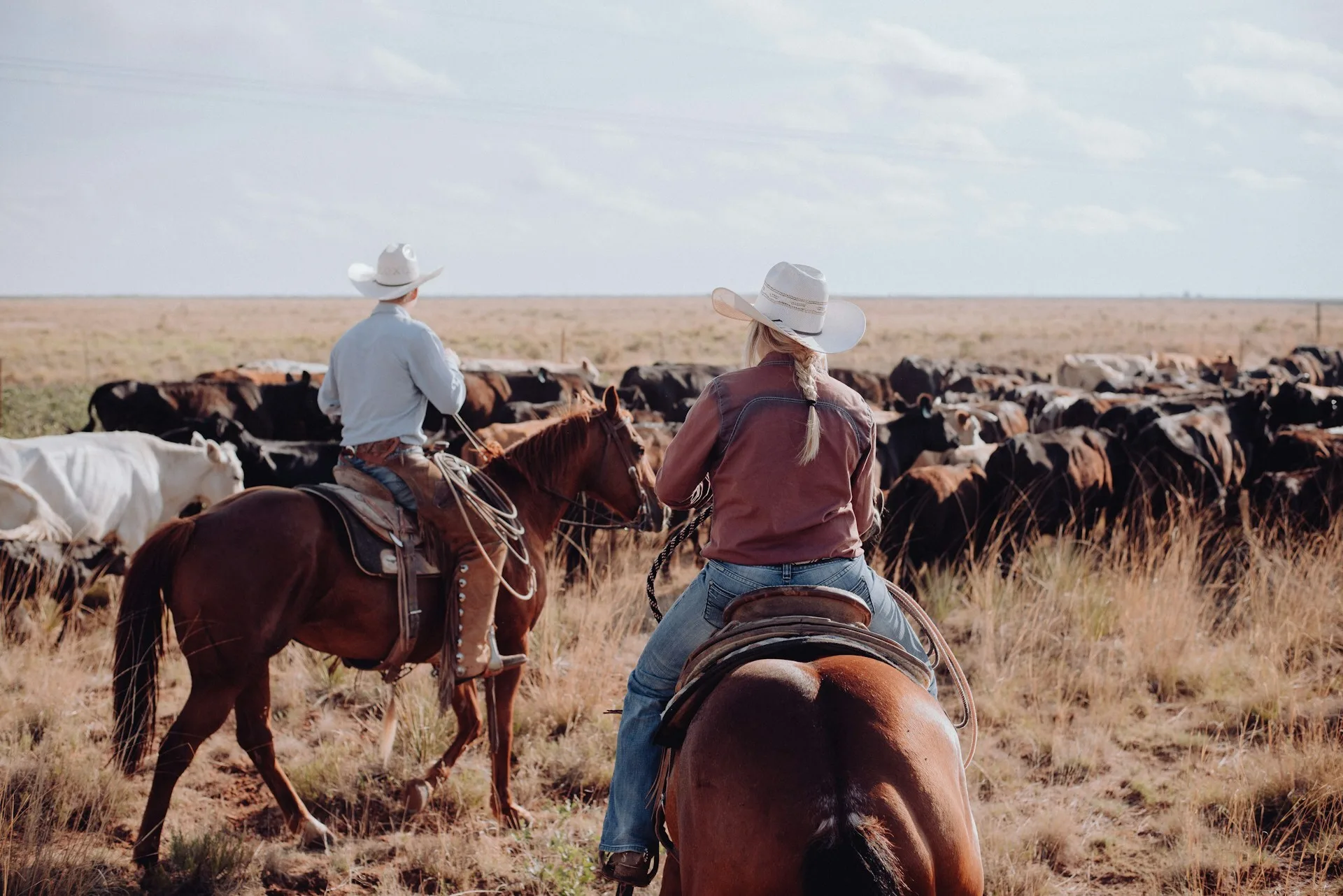 Een cowboy en een cowgirl op paarden bij een ranch in Texas