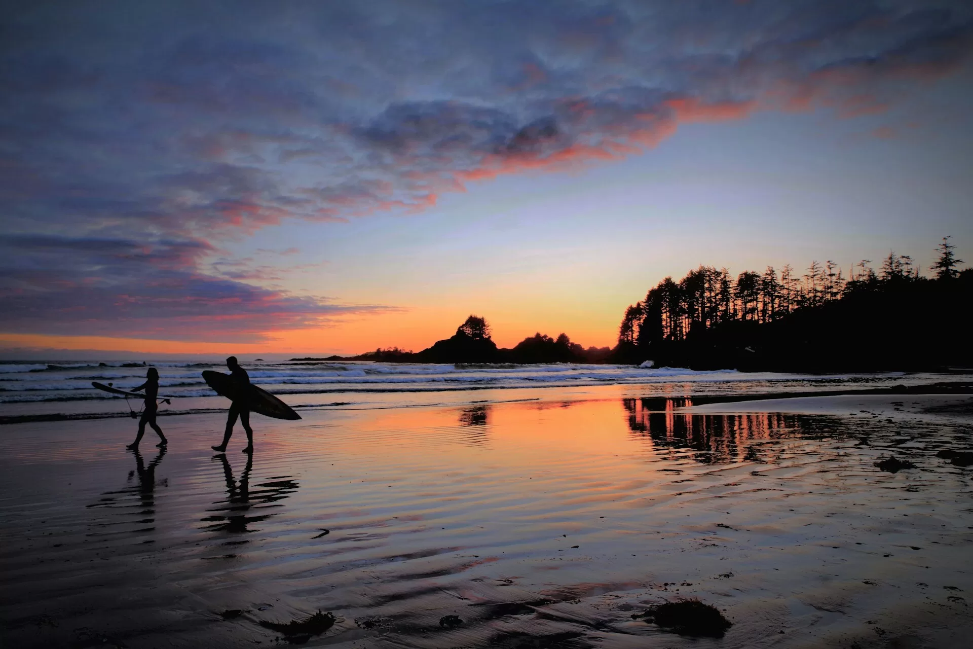 Surfers op het strand van Tofino tijdens een zonsondergang