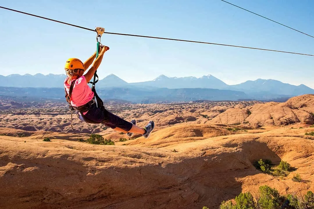 Een vrouw die tokkelt met uitzicht op de iconische rode rotsformaties van Moab op de achtergrond