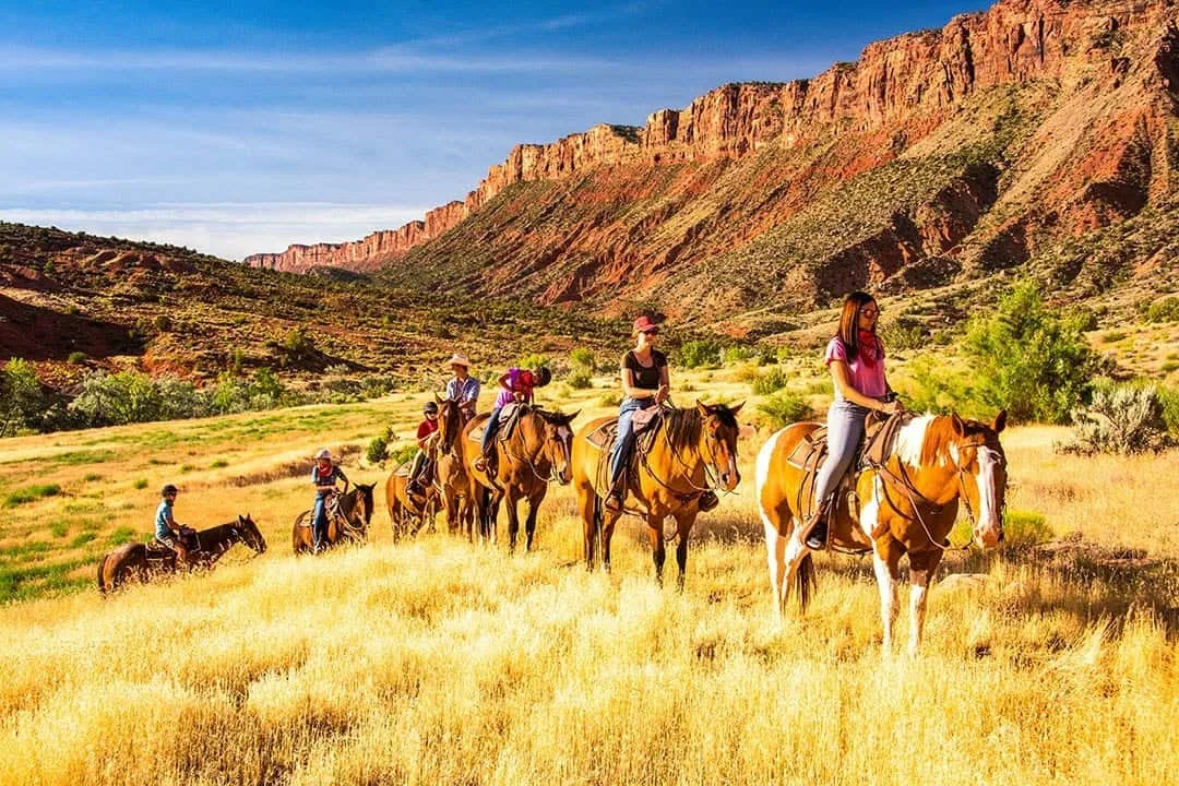 Groep ruiters die Paardrijden in Arches National Park, met rode rotsen van Moab op de achtergrond