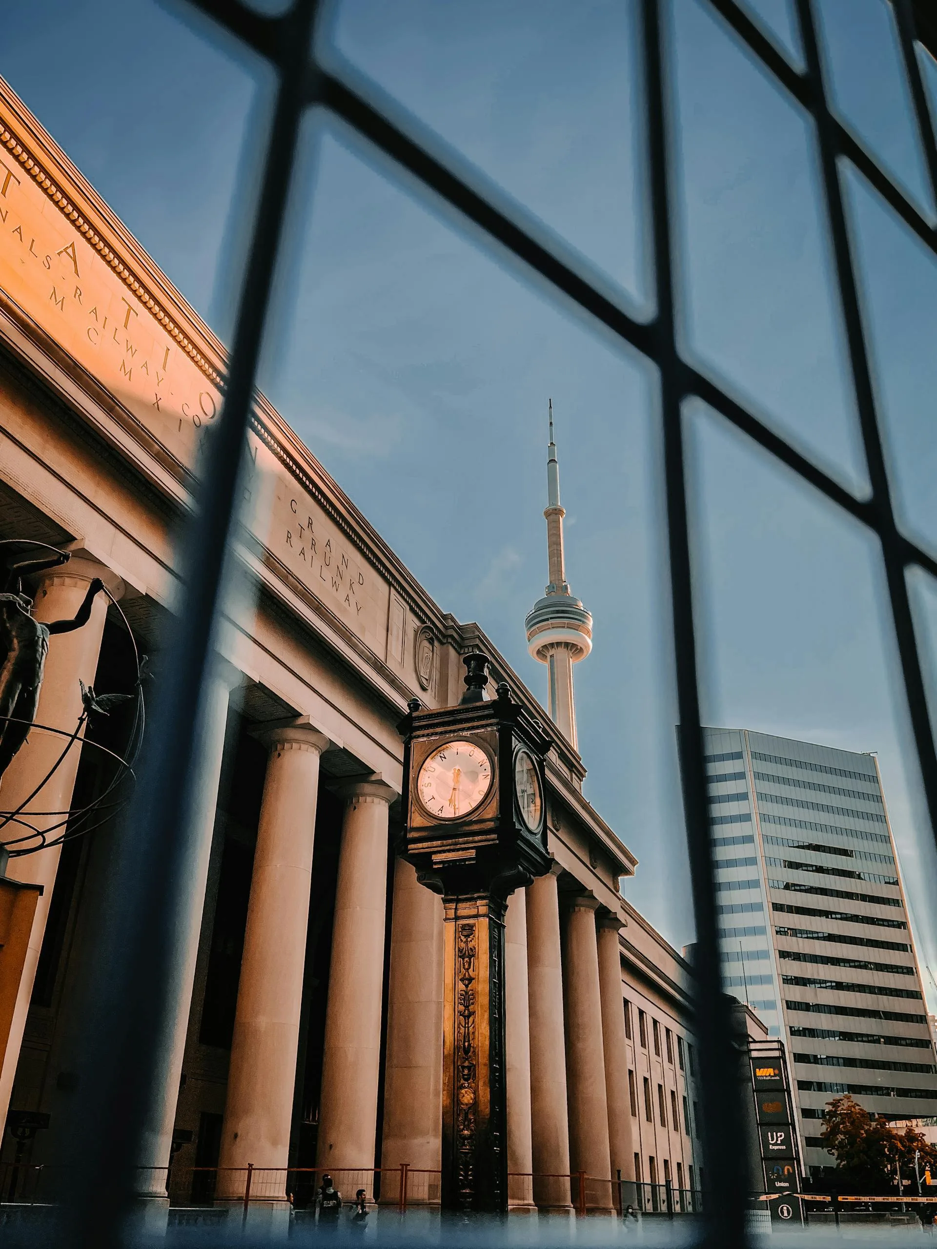 De CN Tower en de stationsklok weerspiegeld in de ramen van het treinstation in Toronto.