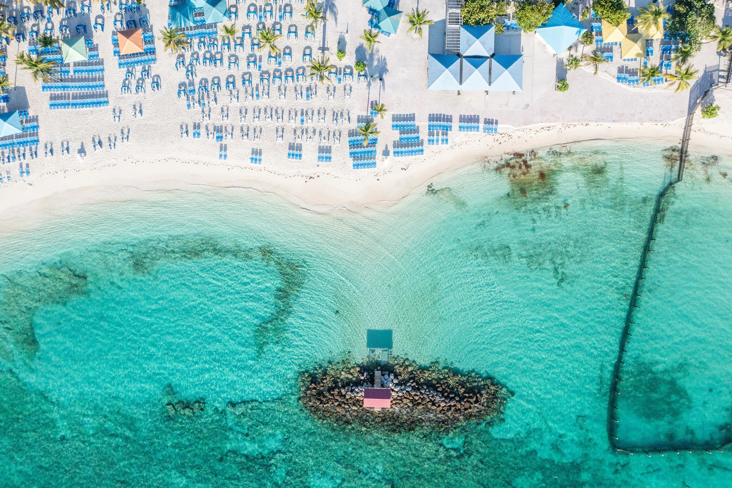 Het strand van Princess Cay met helderblauw water op de Bahama's van bovenaf