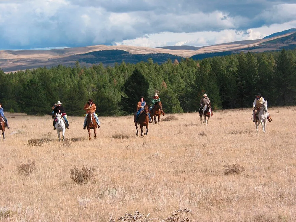 Mensen op paarden in de weides nabij de Circle Bar Guest Ranch in Hobson