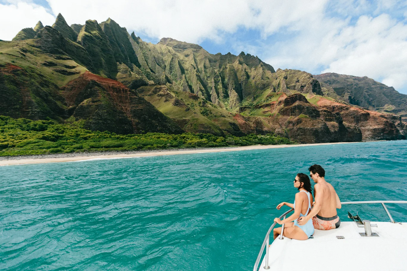 Jong stel zittend op boot varend langs de kust van Hawaii