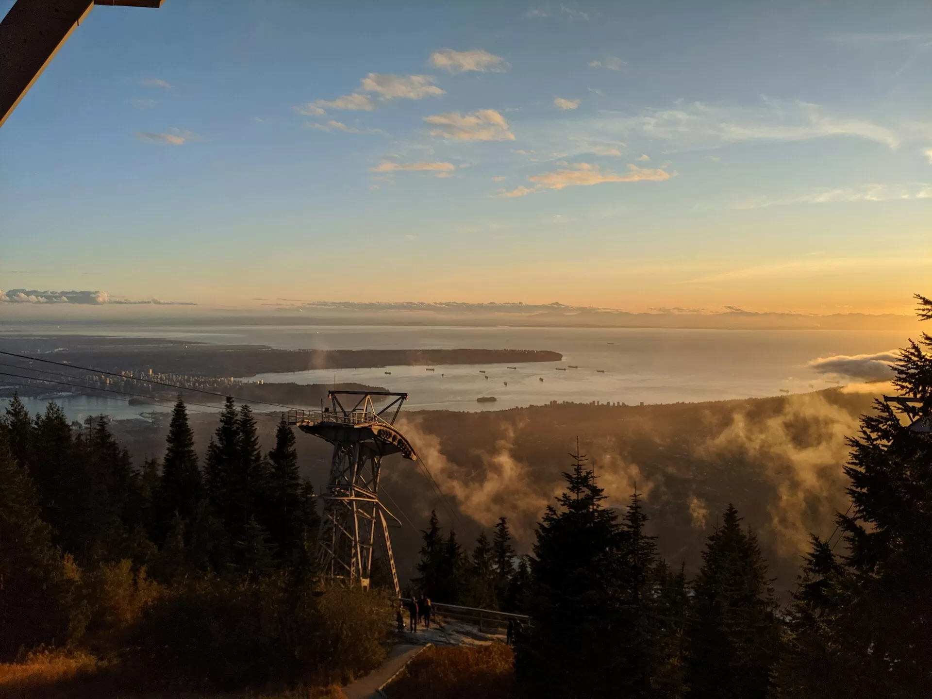 Grouse Mountain bij zonsondergang, met uitzicht op water en de stad Vancouver in de verte