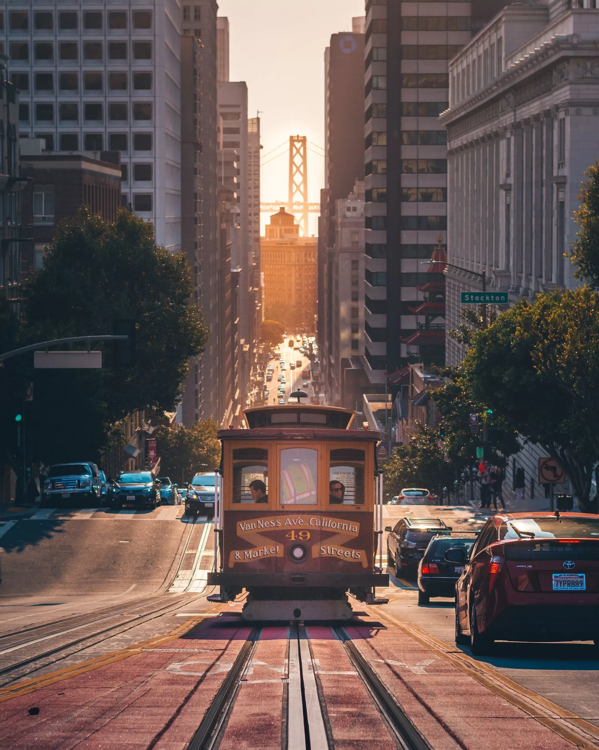 Cable Car in San Francisco met de Oakland Bay Bridge in de avondzon op de achtergrond