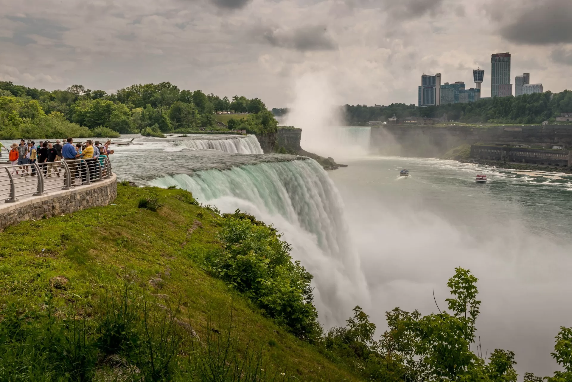 Publiek op uitkijkpunt bij de Niagara Falls in New York State met de hoge hotels op de achtergrond