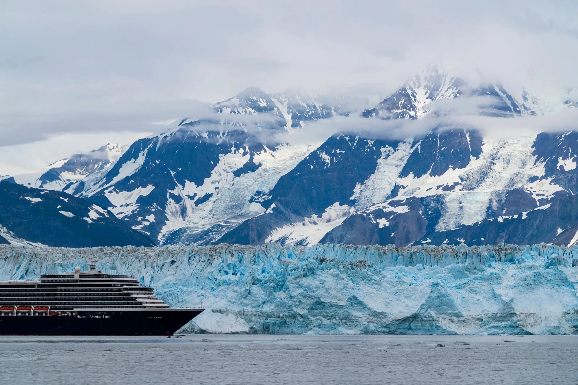 De wateren van Alaska waar een cruiseschip door vaart, je ziet ijsrotsen op de achtergrond