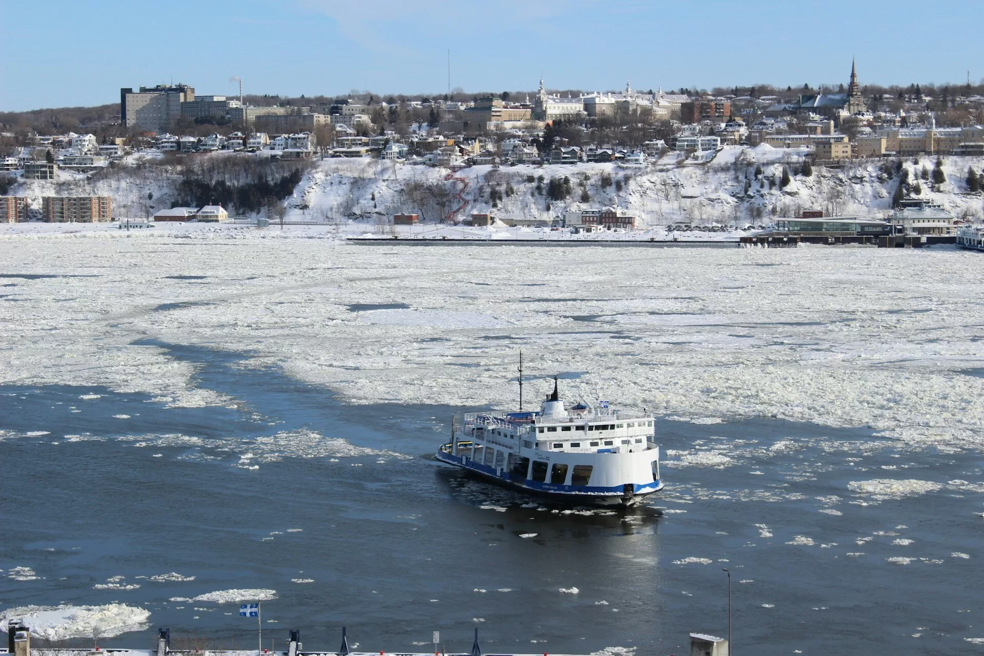 Guided cruise in Quebec City met bevroren water en uitzicht op de besneeuwde stad en historische gebouwen.