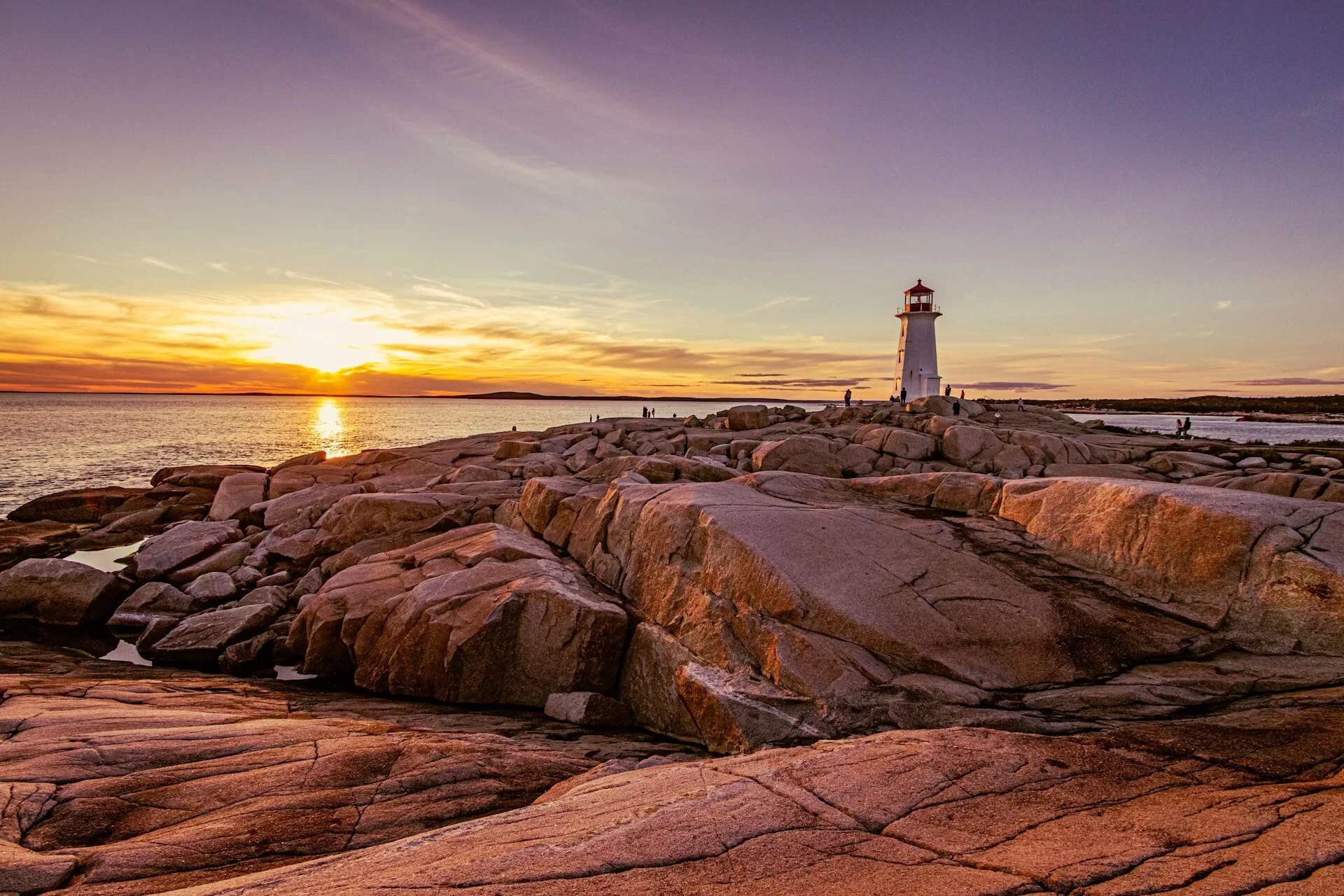 Een vuurtoren op de rotsen langs het water van Peggy's Cove tijdens een zonsondergang