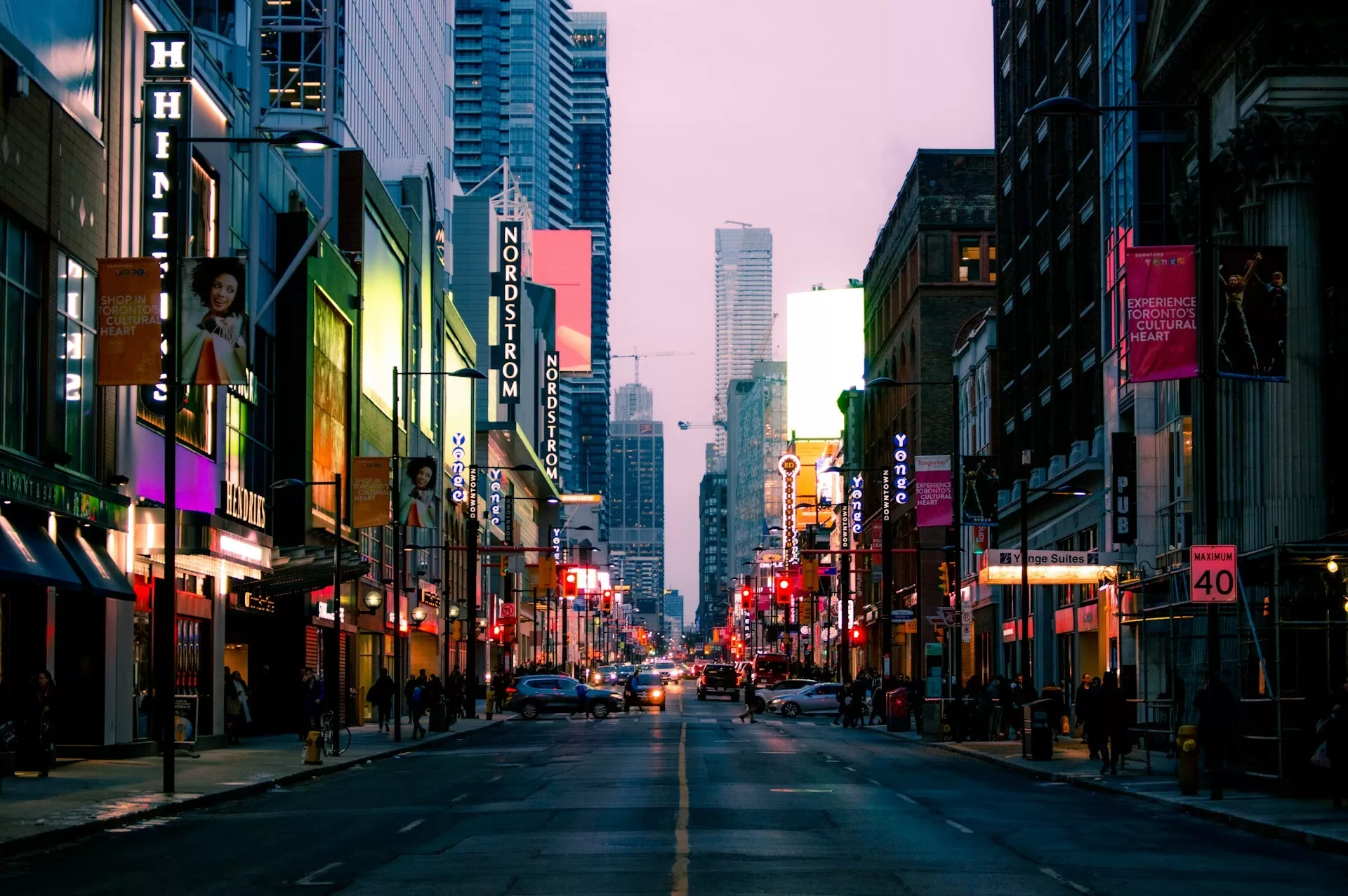 Een winkelstraat in downtown Toronto met gevelverlichtingen en lila gekleurde lucht tussen de gebouwen