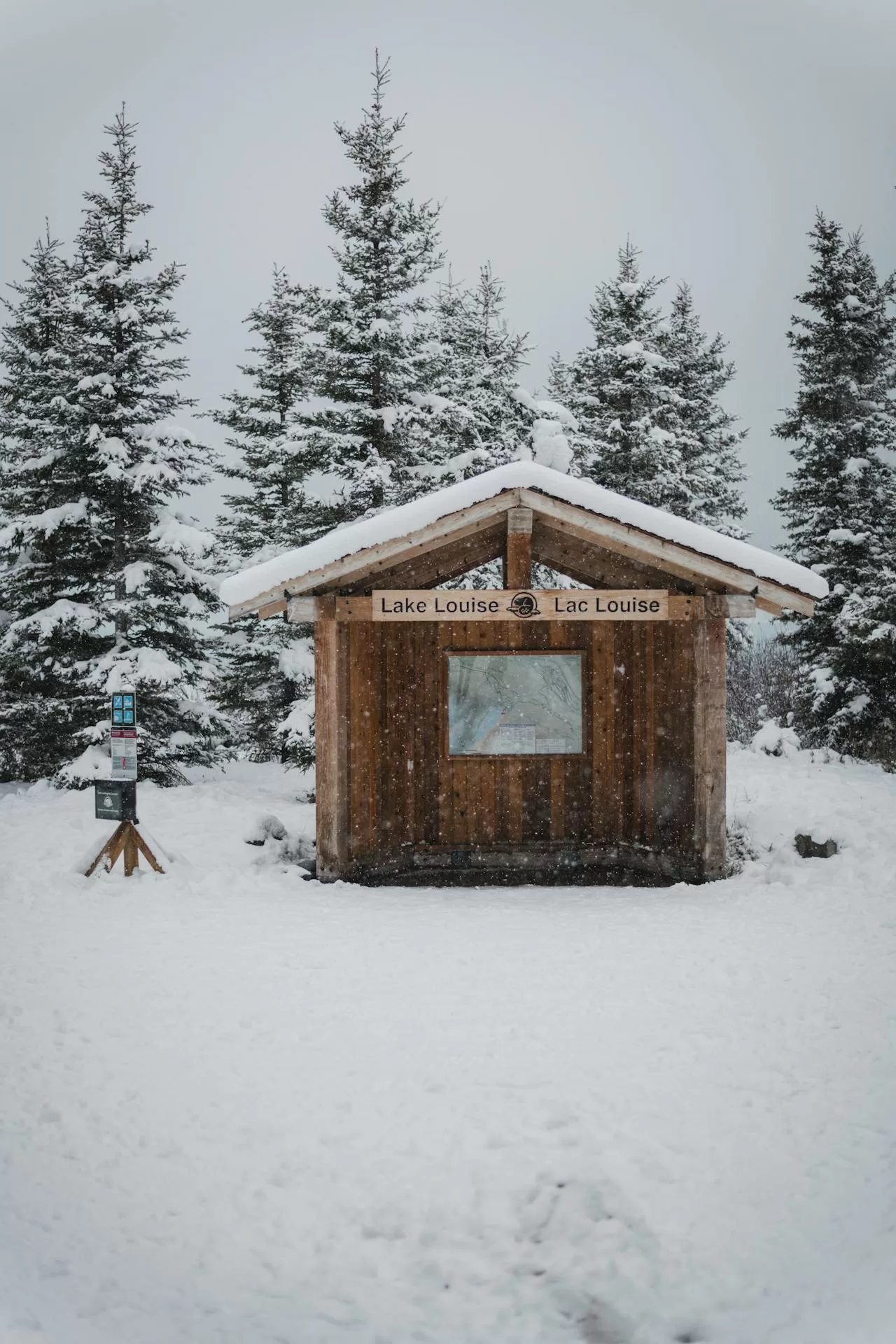 Een besneeuwd huisje met een kaart van de omgeving in Lake Louise