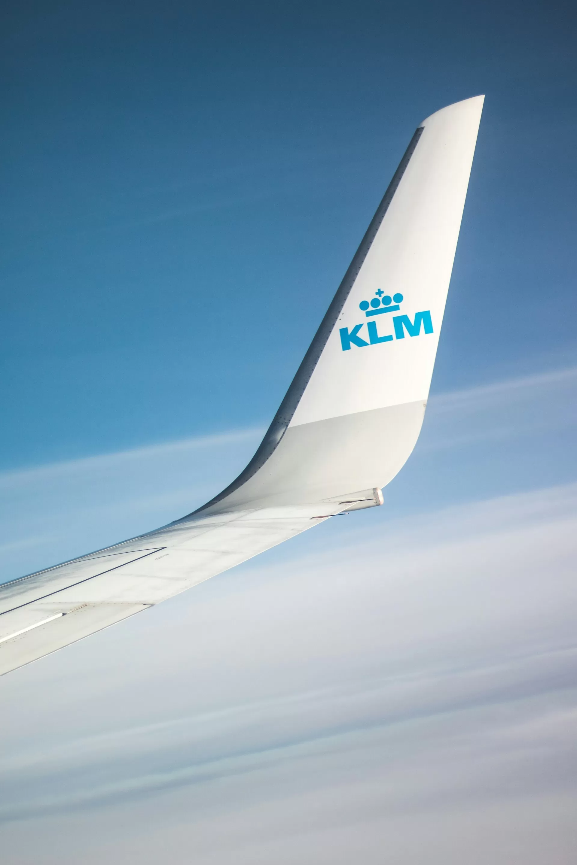 KLM vleugel in de lucht met uitzicht op de wolken tijdens de vlucht