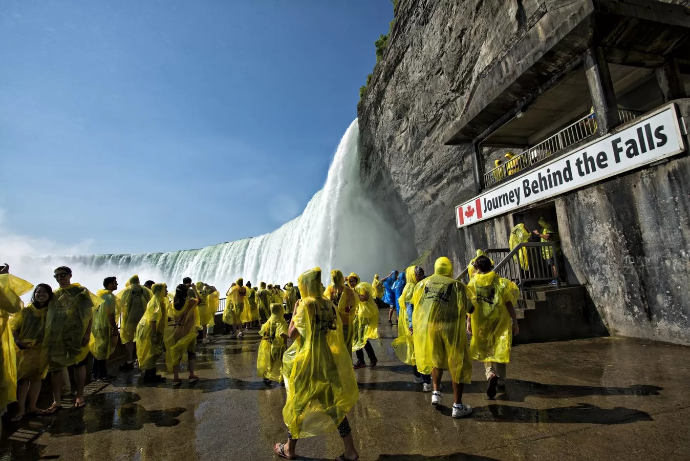 Toeristen op uitkijkplatform met uitzicht op de indrukwekkende Niagara Falls en mistige waterval op de achtergrond
