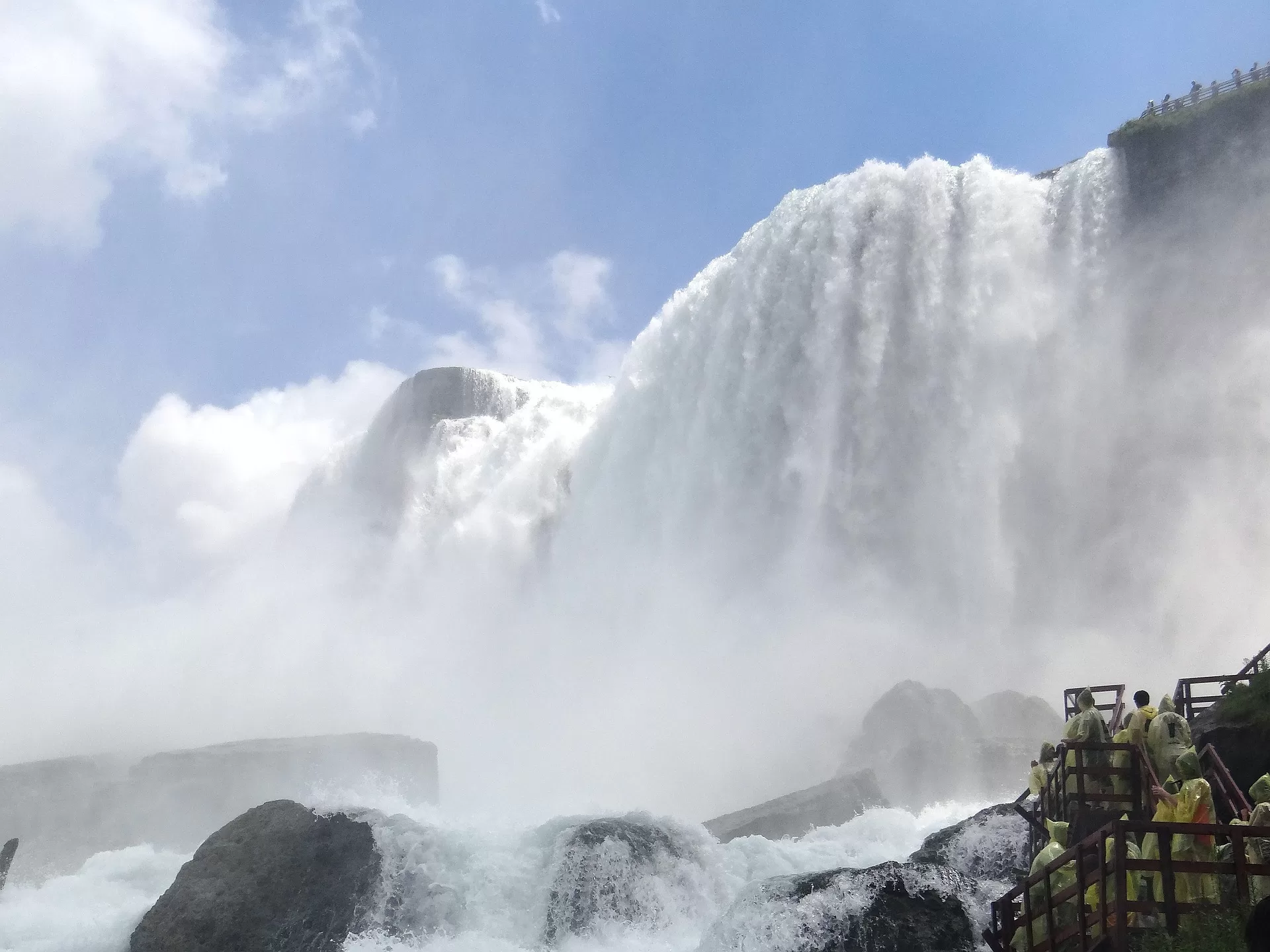 Indrukwekkend uitzicht op de krachtige Niagara Falls met nevel en stromend water onder een blauwe lucht