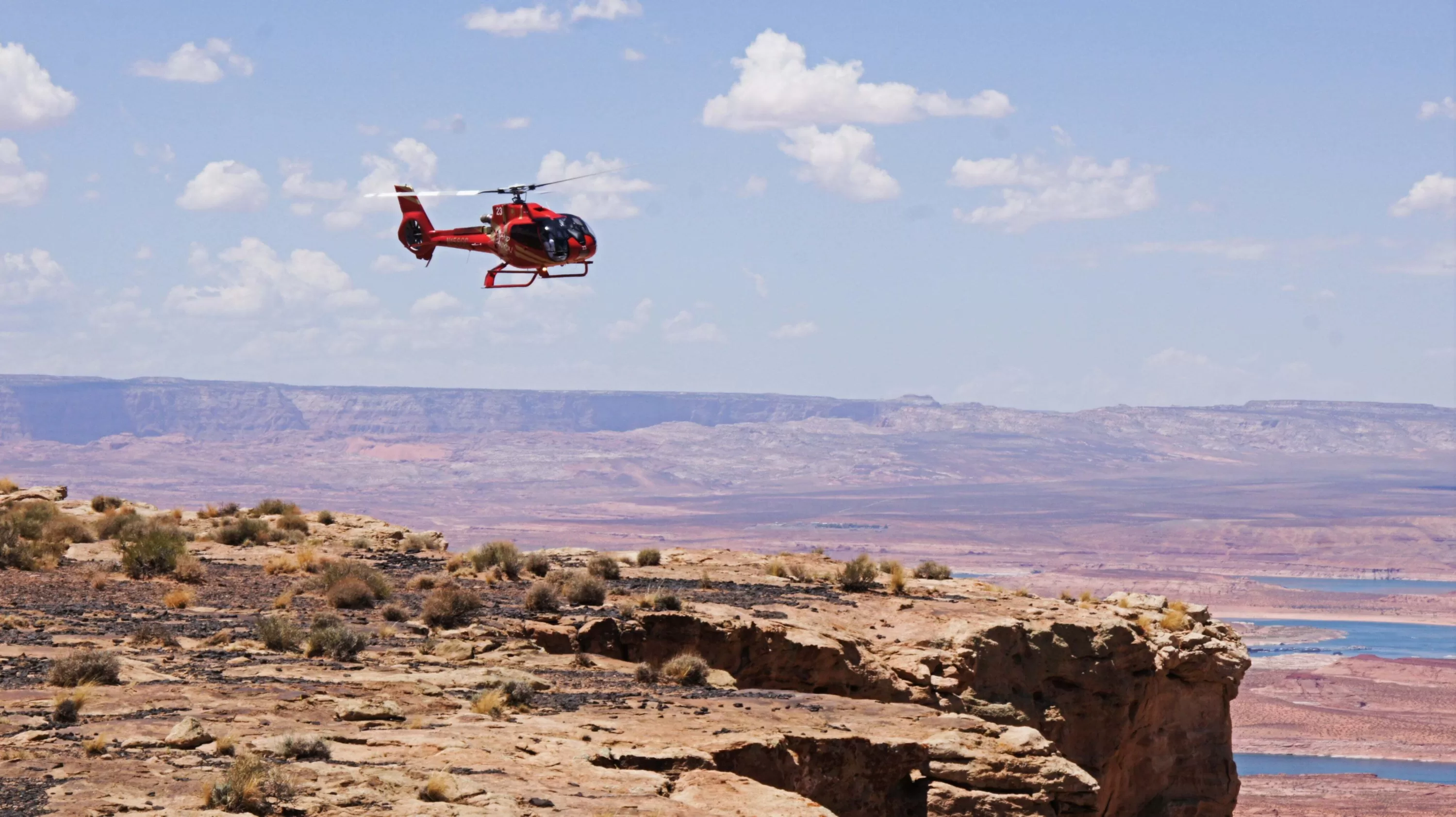 Rode helikopter vliegt boven de Grand Canyon met uitzicht op de indrukwekkende rotsformaties