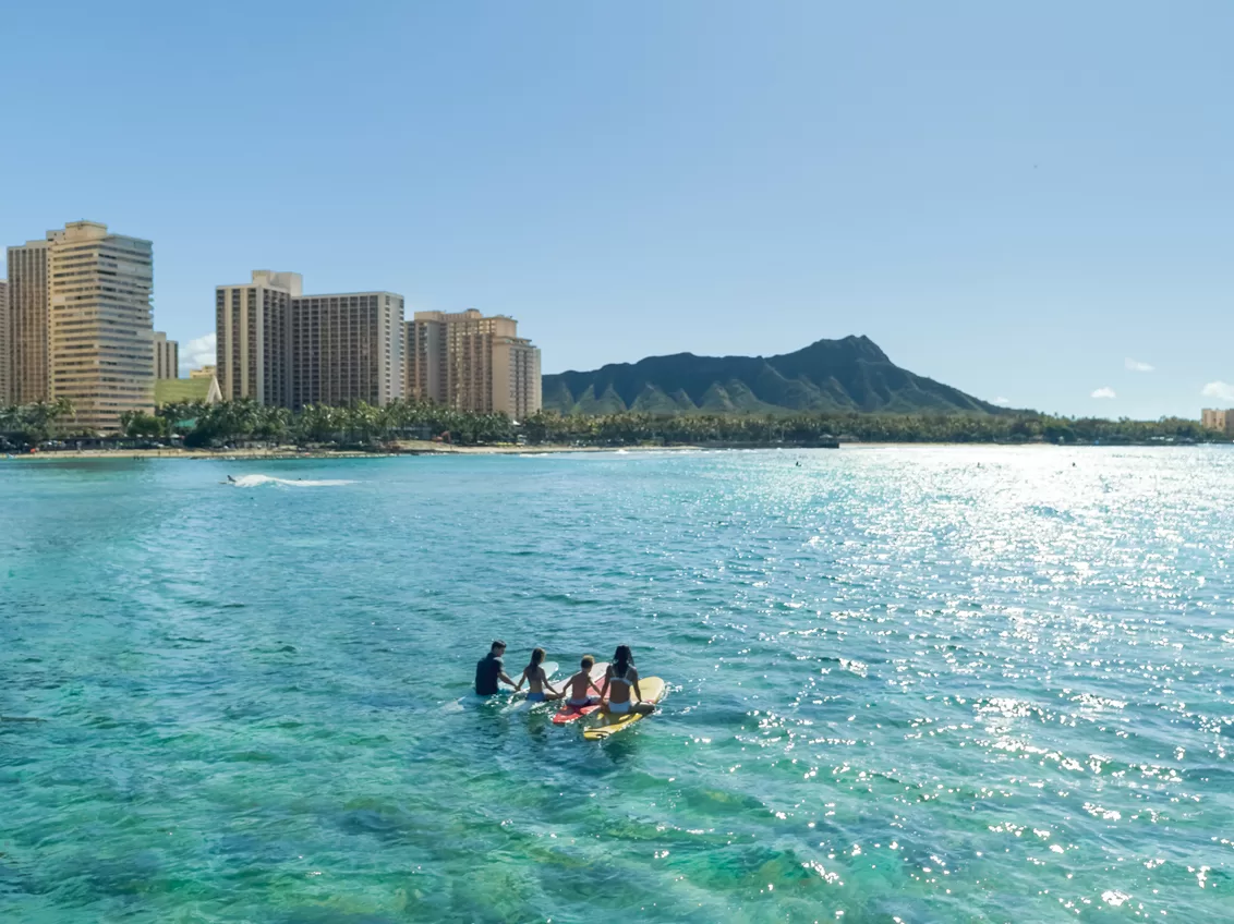 Surfen op Waikiki Beach met op de achtergrond wolkenkrabbers en de vulkaan