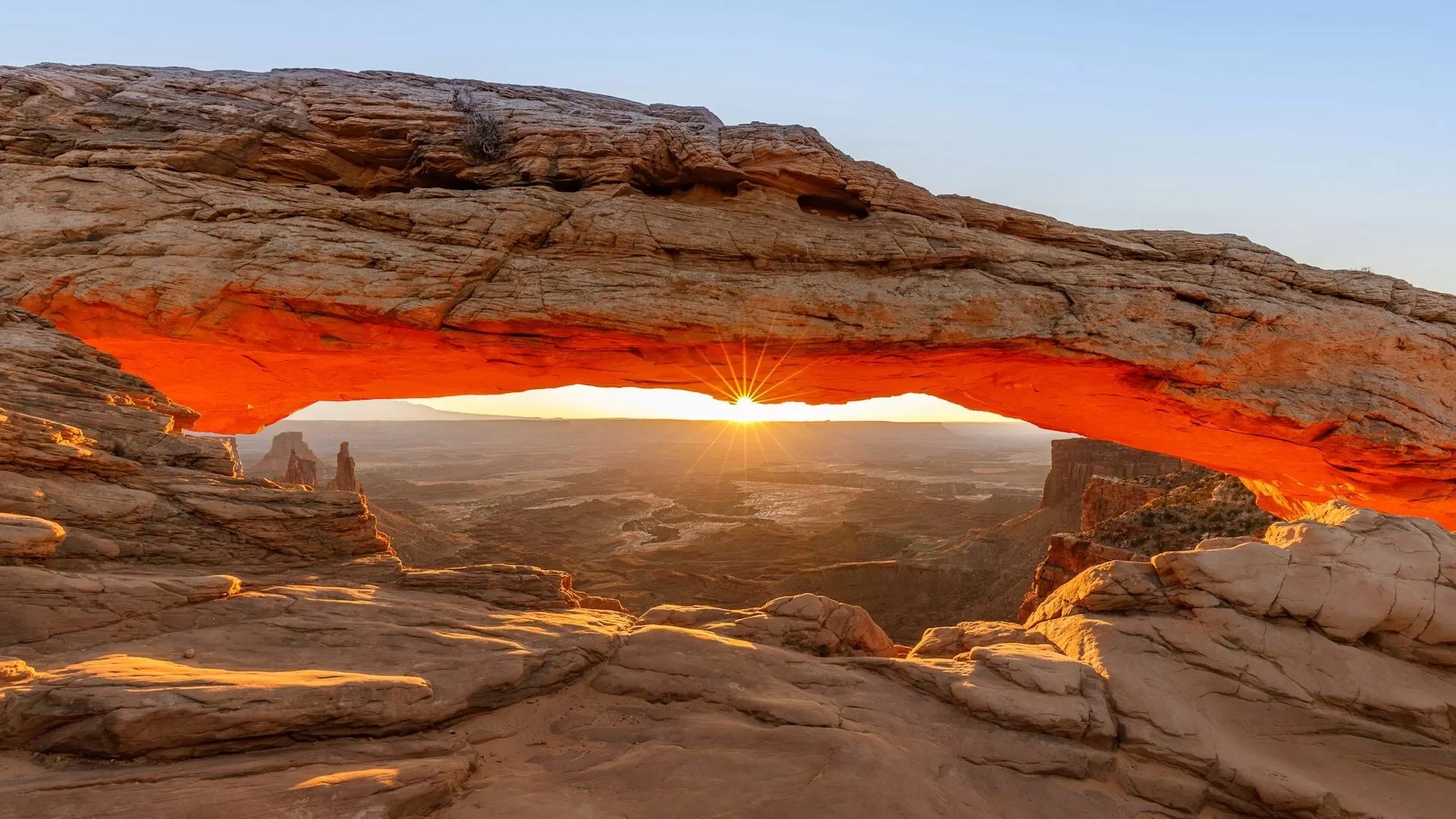 Mesa Arch deels rood verlicht door de ondergaande zon in Arches National Park Utah