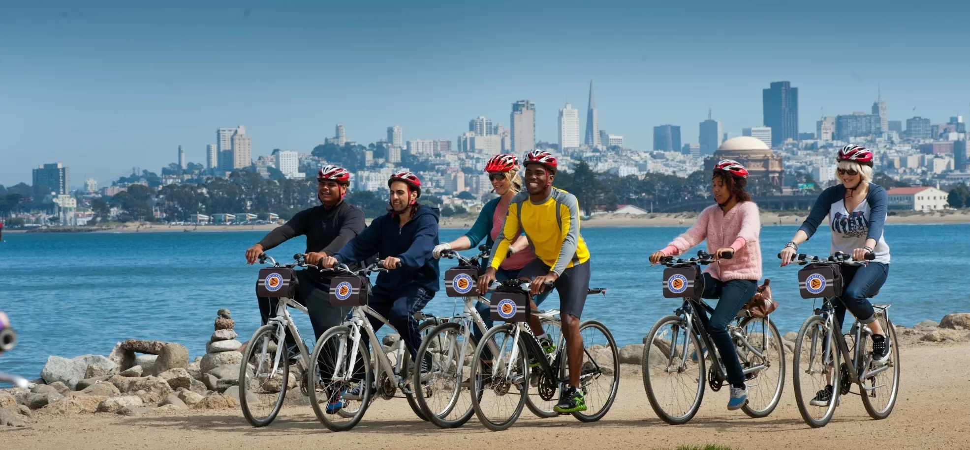 Groep mensen fietsen met San Francisco skyline op de achtergrond tijdens zonnige dag