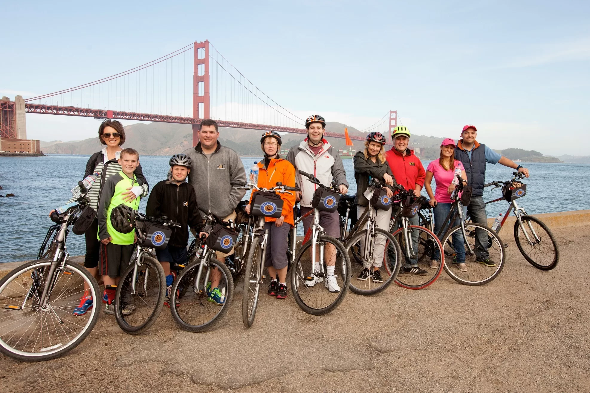 Mensen met fietsen poseren bij Golden Gate Bridge vanaf de zijkant te zien op een bewolkte dag in San Francisco