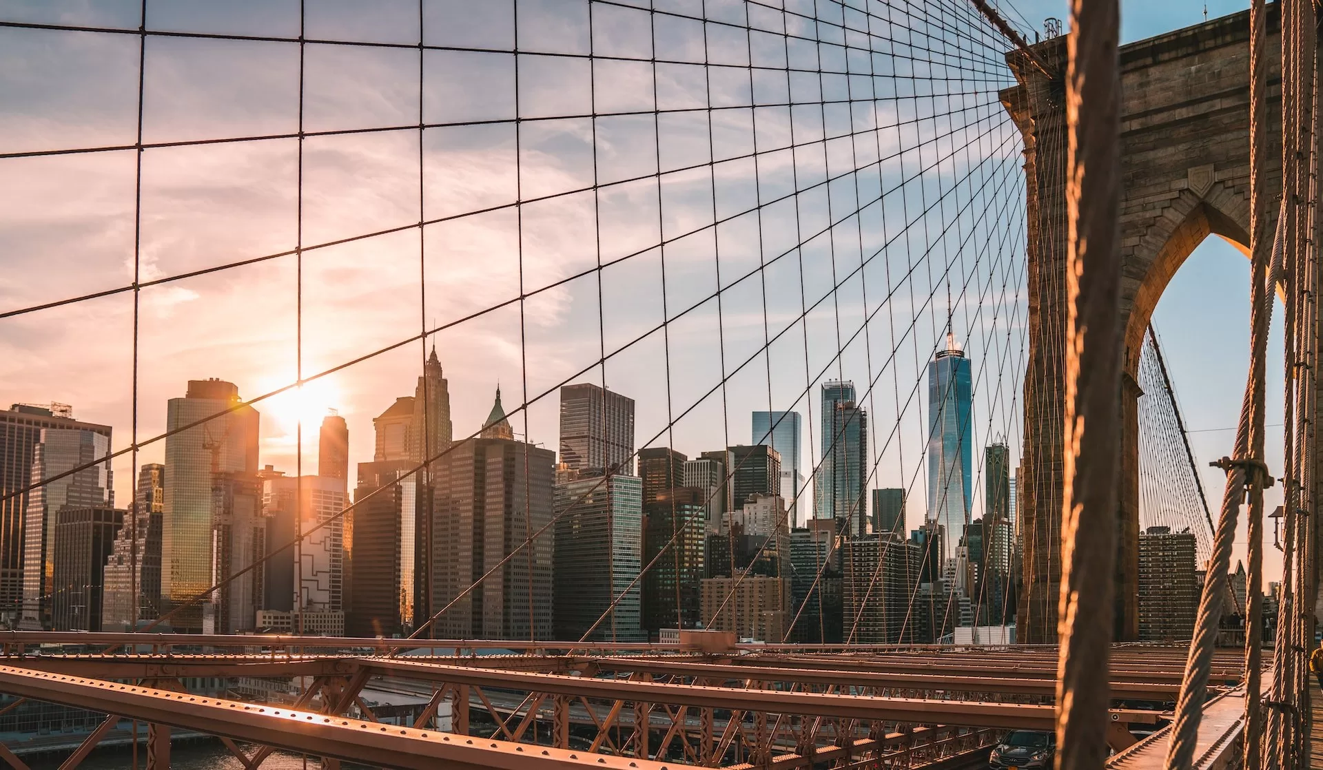 Uitzicht vanaf de Brooklyn Bridge op de skyline van Manhattan met ondergaande zon.