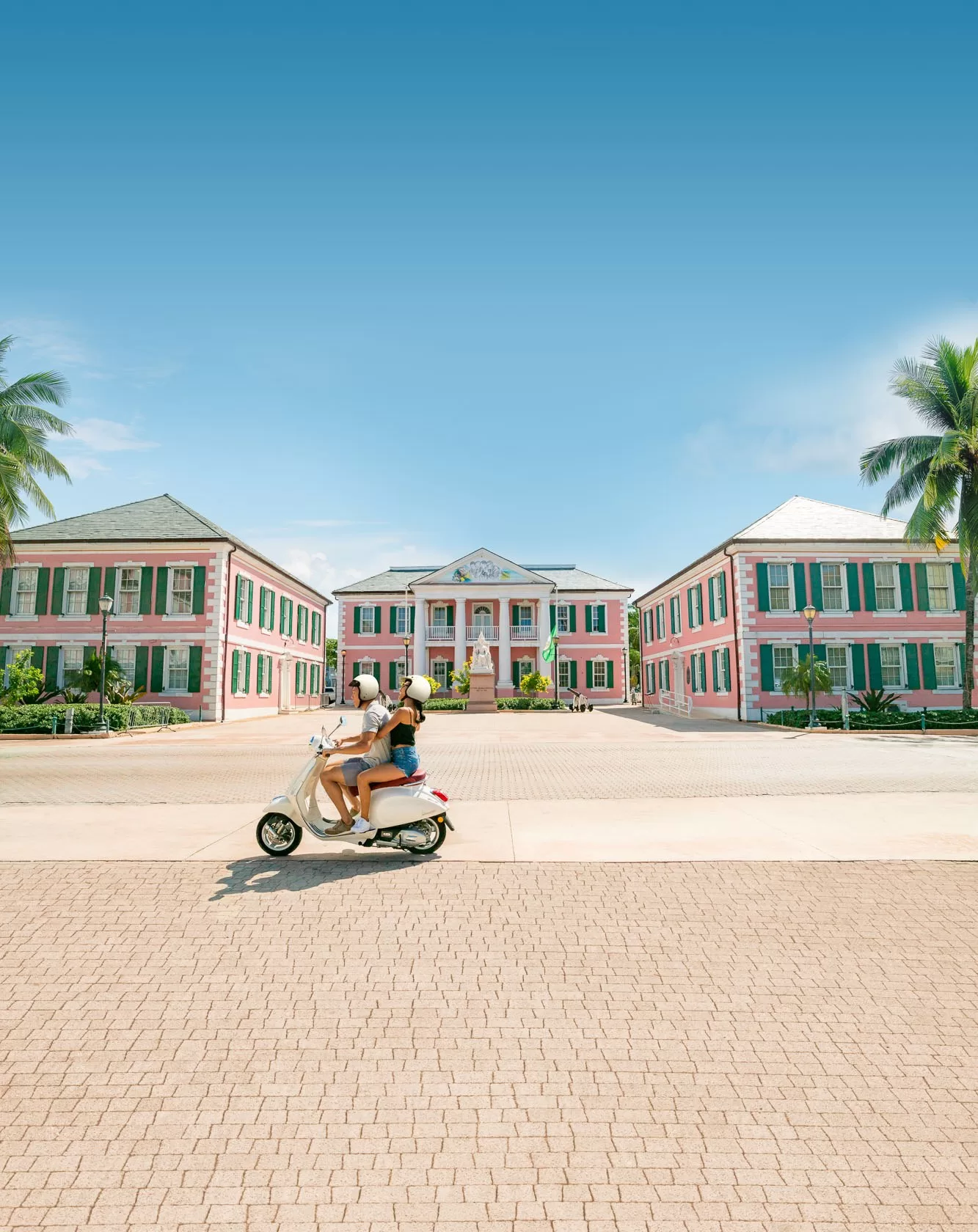 Stelletje op een scooter voor een groot roze gebouw in Nassau, de Bahama's