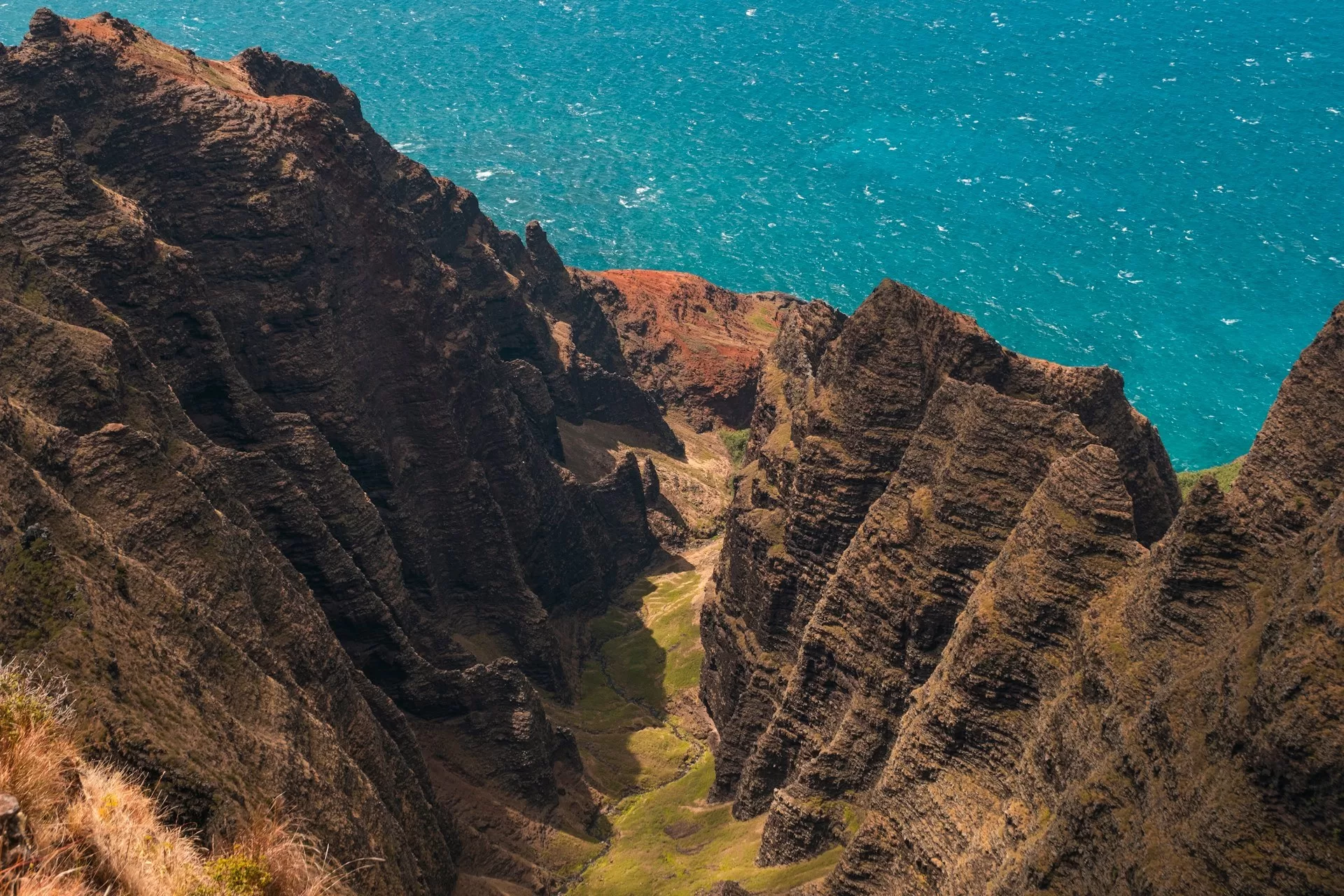 Blik van bovenaf op de grillige bruin/groene kustlijn van de Napali Coast op Kauai, Hawaii